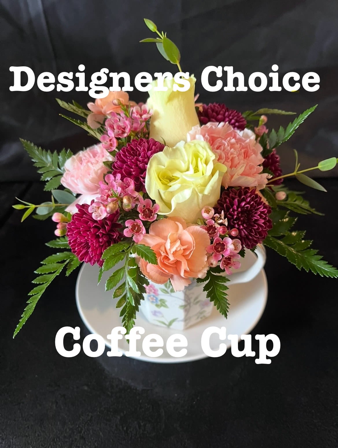 Small floral arrangement in a floral coffee cup and saucer