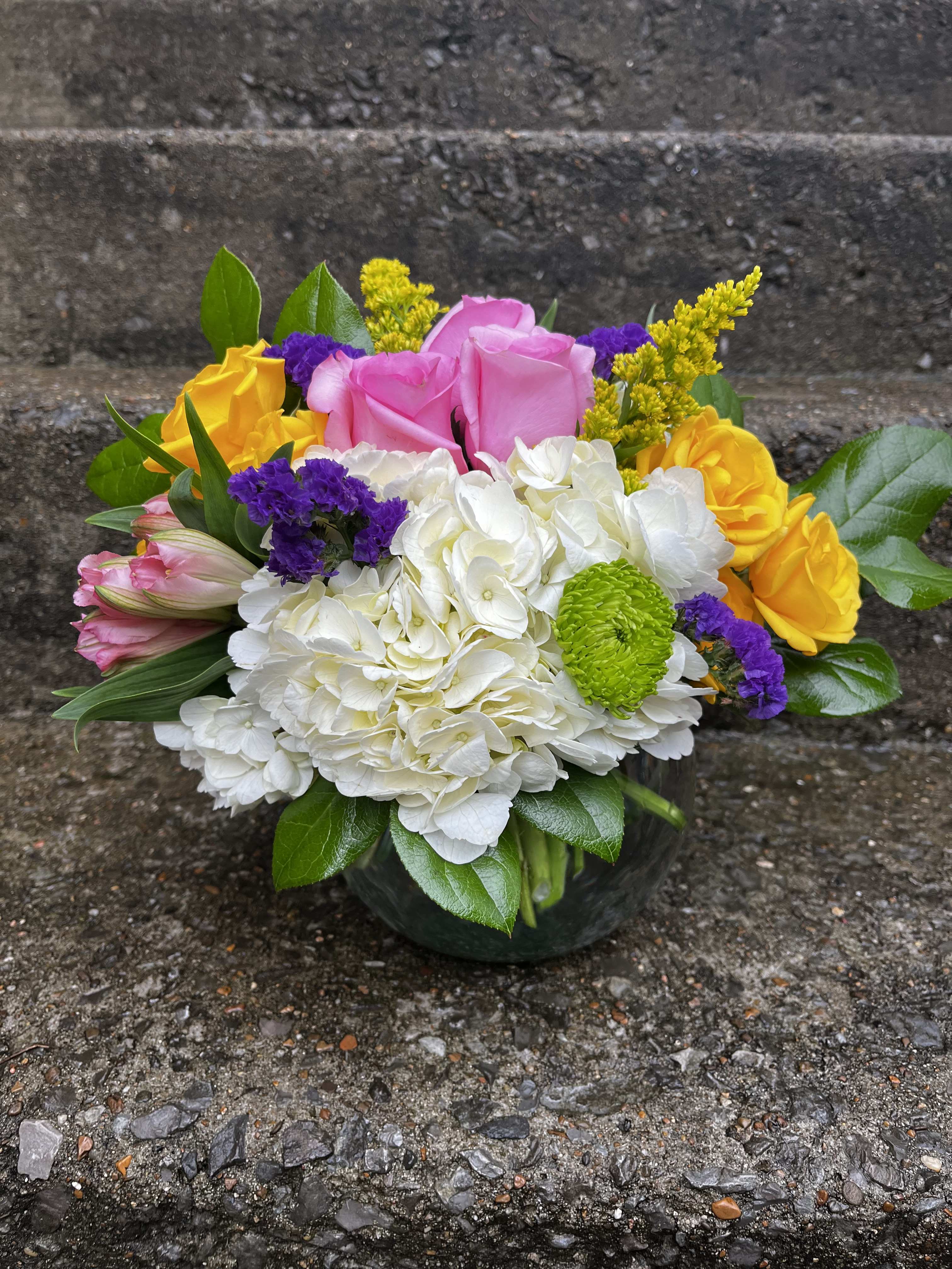 Colorful bouquet of roses, hydrangea, and mums in a glass vase