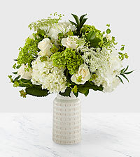 Pure Grace - Through luminous white blooms and luscious greens, our Pure Grace Bouquet shines with elegant beauty. A divine array of white hydrangea, cream roses, green mini hydrangea, and Queen Anne's lace are set in an ivory ceramic vase to leave a lasting impression on its recipient. With each flower selected to complement the others, this arrangement makes a memorable gift for any occasion.   Bouquet is approx. 14"H x 12"W.