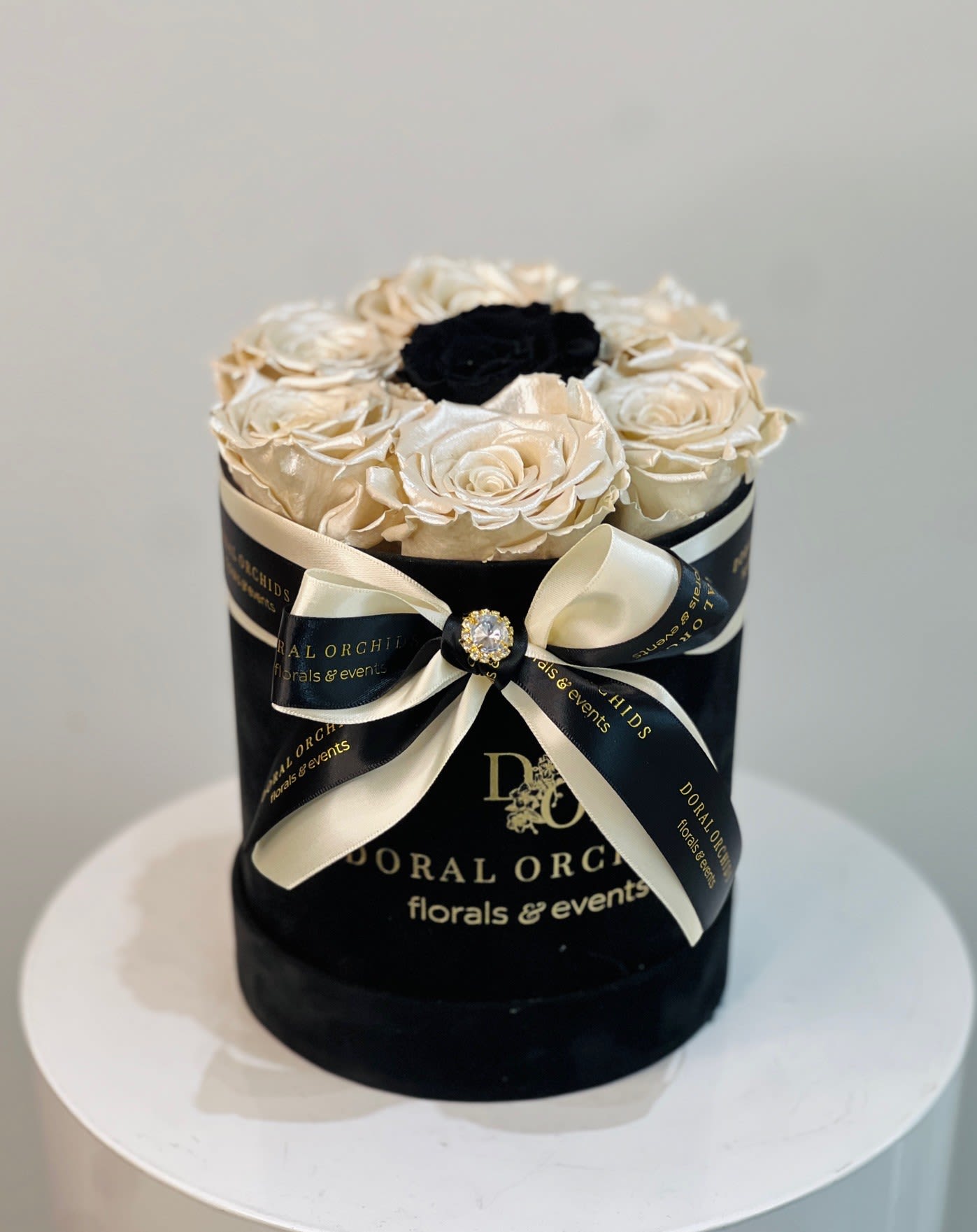 Black hatbox with cream roses and a black center rose, tied with ribbon