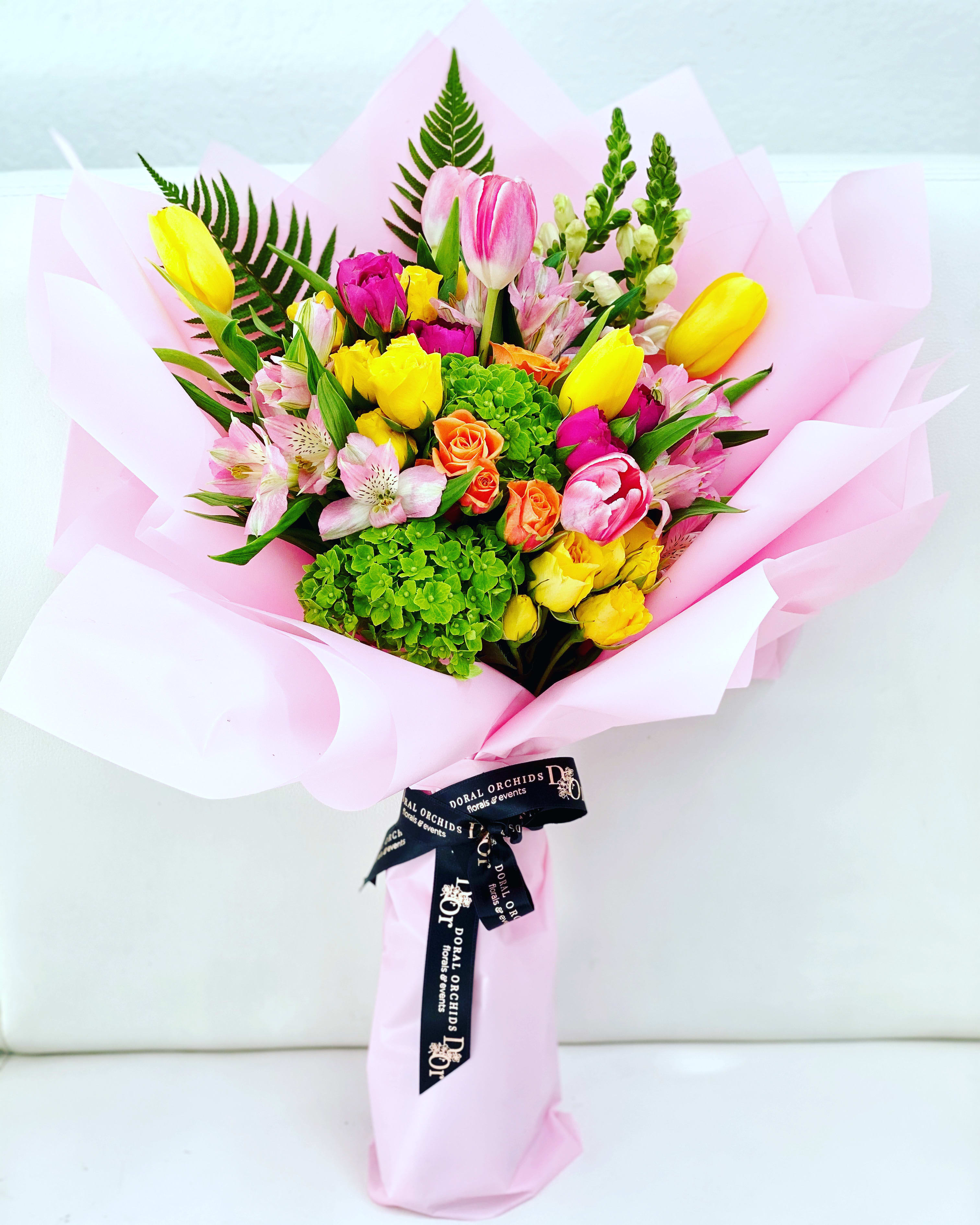 Mixed bouquet of tulips, roses, and alstroemeria wrapped in pink paper