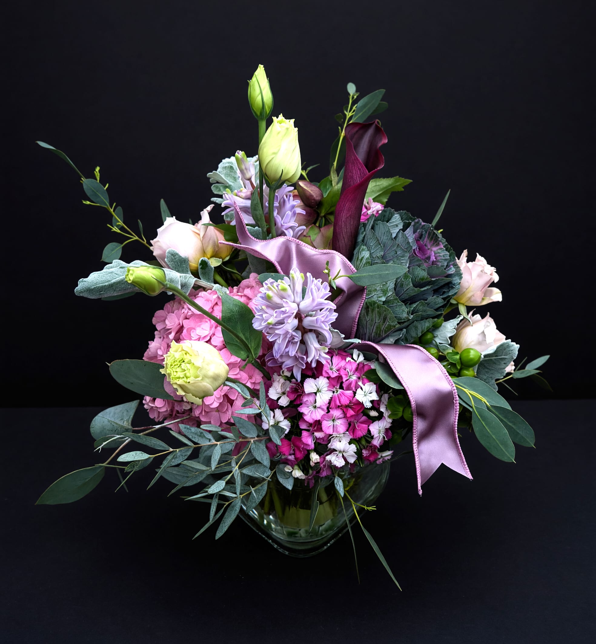 Mixed bouquet with pink, lavender, and white flowers in a glass vase