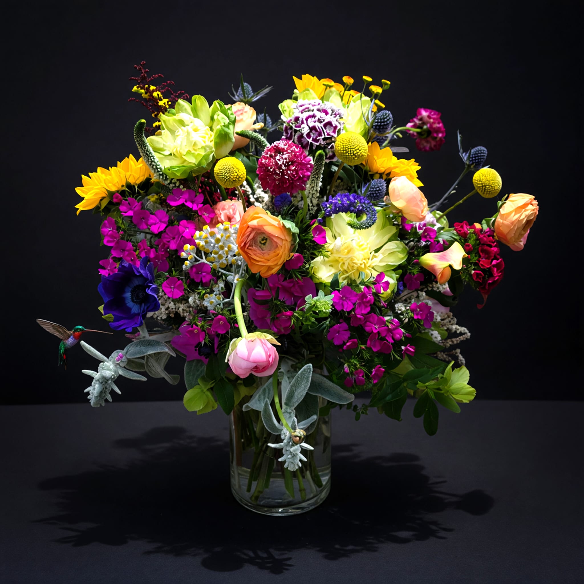 Ladybird - Colorful medley of seasonal wild flowers designed in a clear glass container.