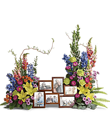 Loving Farewell Photo Tribute Bouquet - DESCRIPTION SIZES Add inspiring color to your loving farewell with this beautiful bouquet of roses, lilies and delphinium in all the shades of the rainbow. A breathtaking accent for beloved framed photos. Green roses, orange spray roses, yellow asiatic lilies, blue delphinium, orange snapdragons, hot pink matsumoto asters, and lavender button spray chrysanthemums are accented with curly willow, myrtle, sword fern, silver dollar eucalyptus, and lemon leaf. Arrangement does not include picture frame.