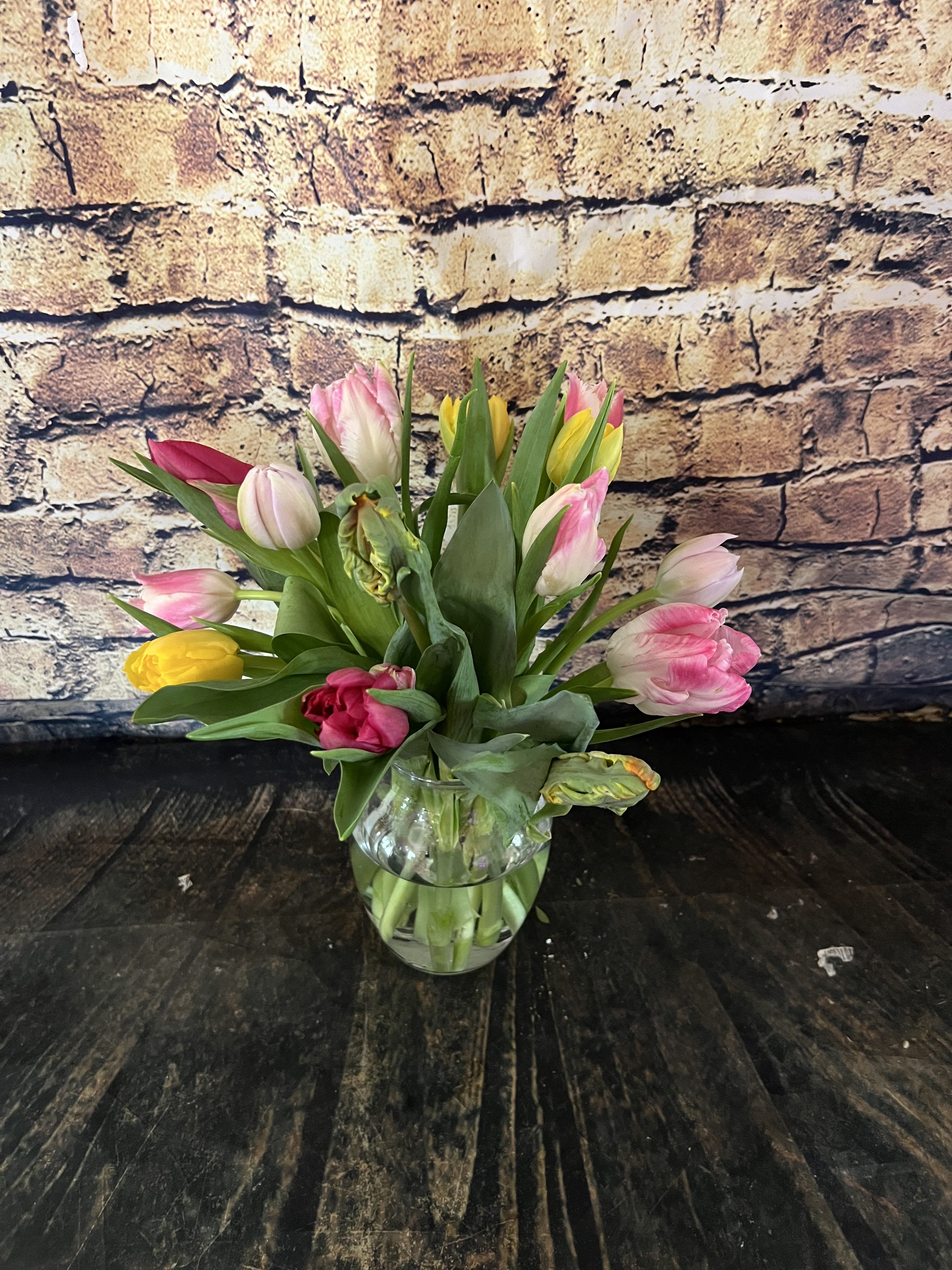 Tulip bouquet in a clear glass vase with pink, yellow, and white blooms.