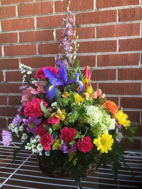 A MEDIUM SIZE SPRING BASKET - A COLORFUL ARRANGEMENT OF FRESH FLOWERS IN A WICKER BASKET.  ACTUAL SPRING FLOWERS MAY VARY FROM PICTURE BASED ON INVENTORY AND SEASON.  THE COLOR SCHEME WILL BE SIMILAR.