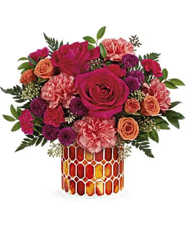 Bouquet of pink and orange flowers in a patterned glass vase