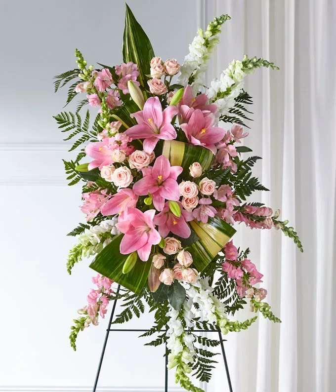 Tall standing floral spray with pink lilies, pale roses, and white snapdragons