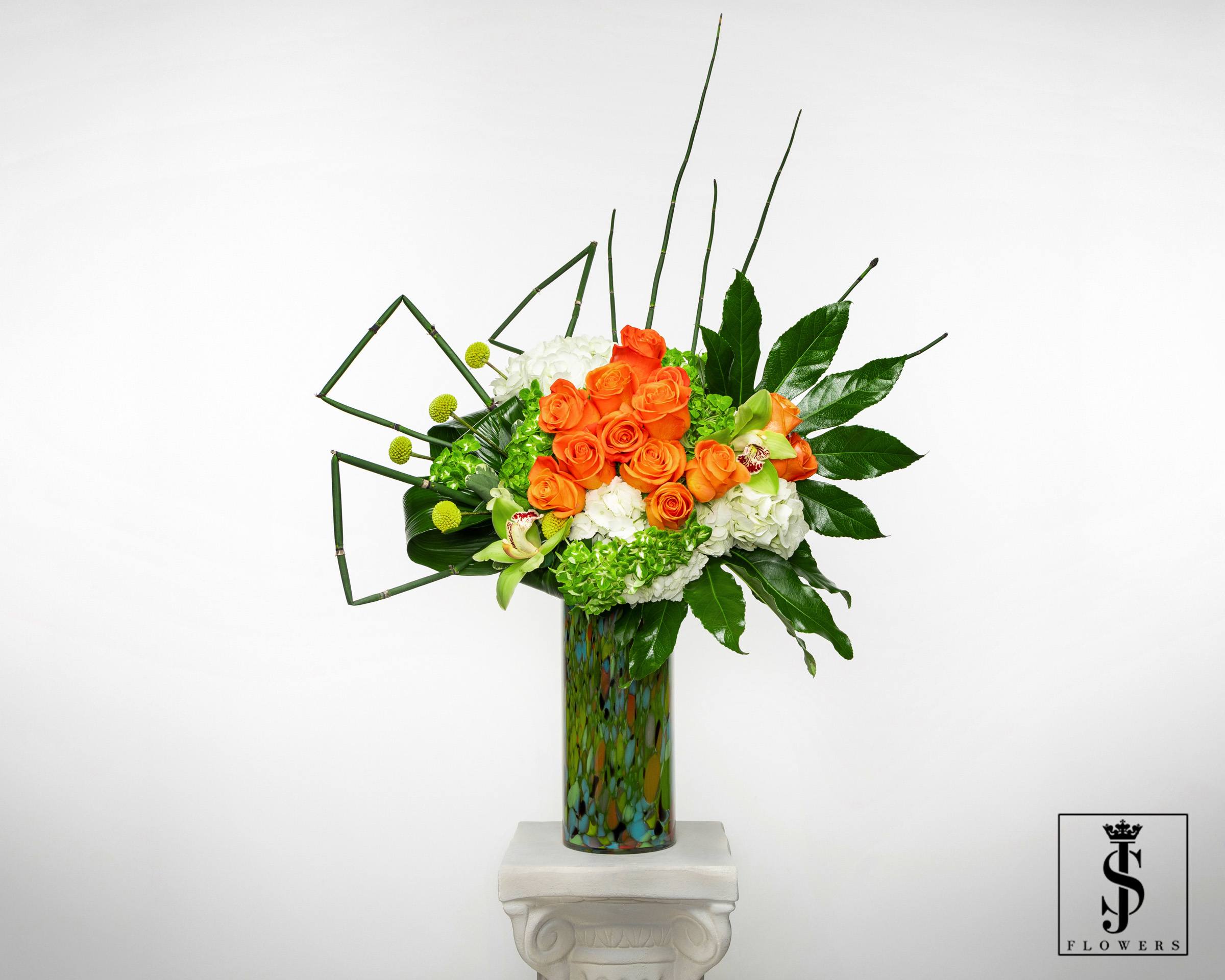 Orange roses and white hydrangeas in a tall patterned vase
