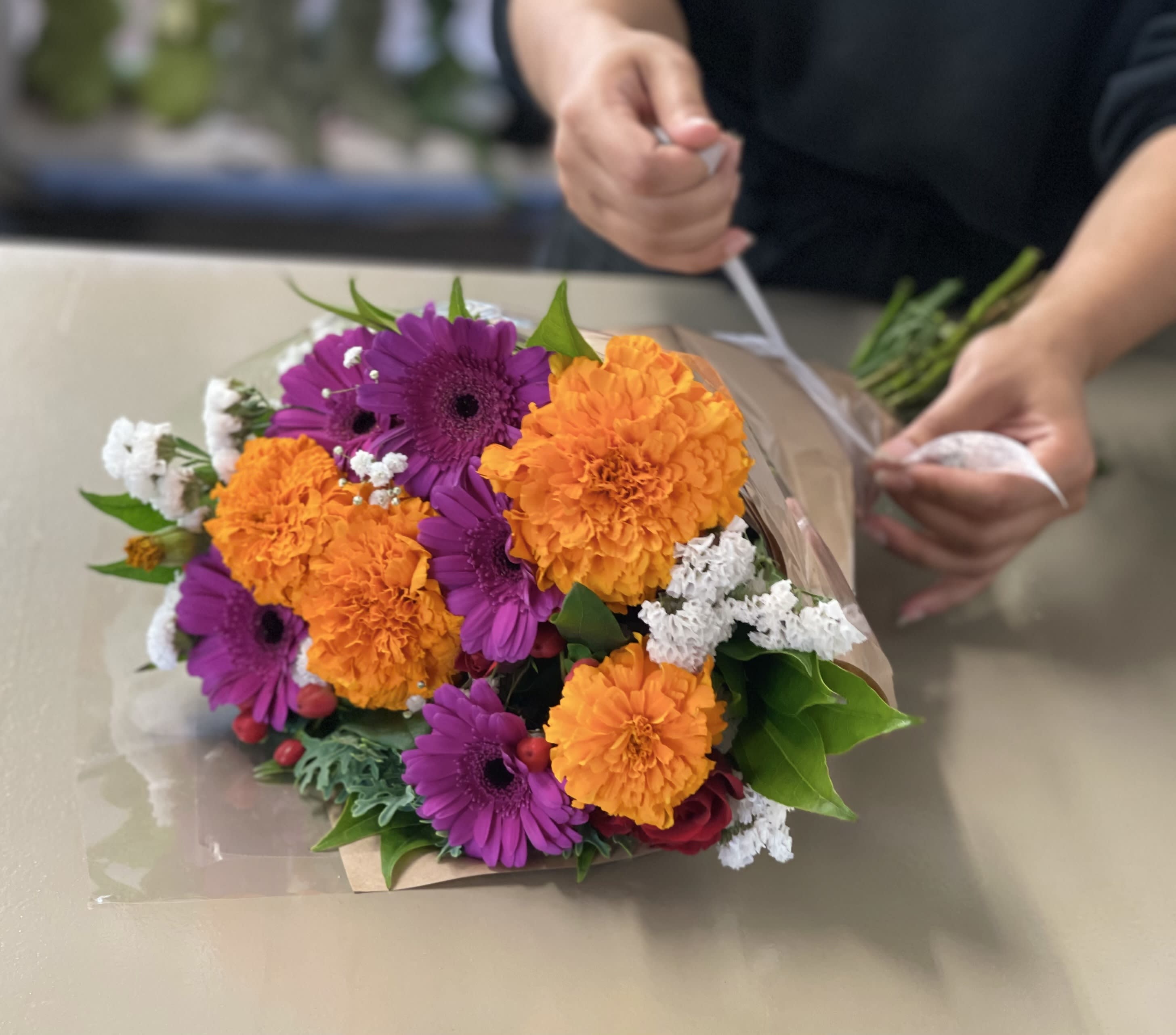 Bouquet of purple gerbera daisies and orange marigolds wrapped in paper