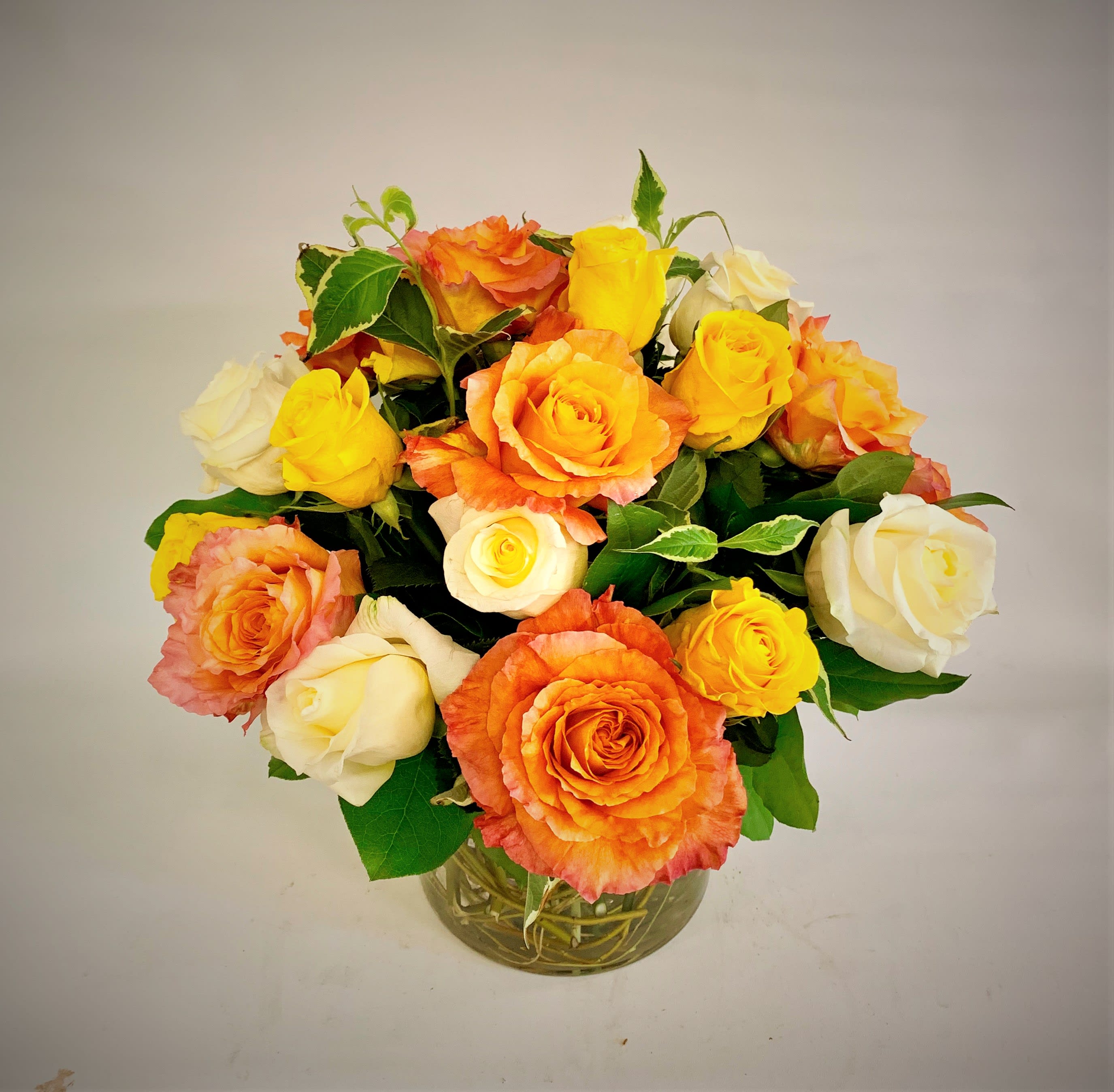 Bouquet of orange, yellow, and white roses in a glass vase