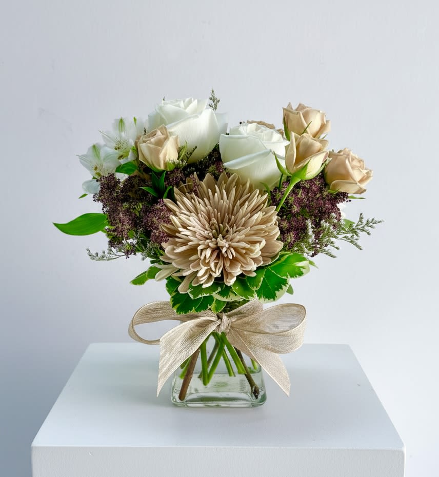 Paddy  - A small clear glass vibe vase filled with a peach cremon, peach spray roses, white alstroemeria and white roses with an accent of chocolate Queen Anne’s lace. 