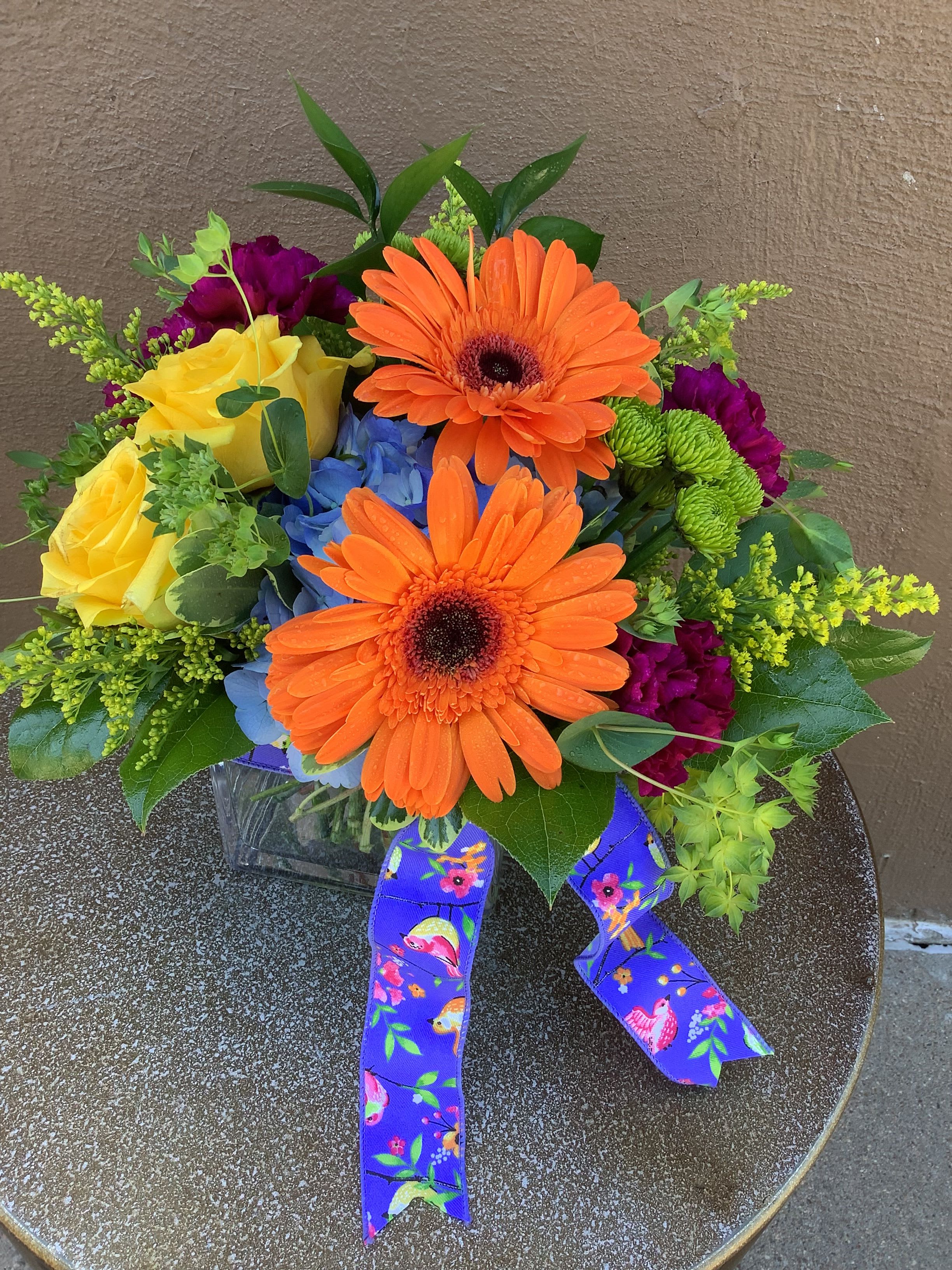 Raspberry Ripple - Bright mixed-color bouquet with gerbera, hydrangea, spray roses, hyacinth and asters, finished with a patterned ribbon.