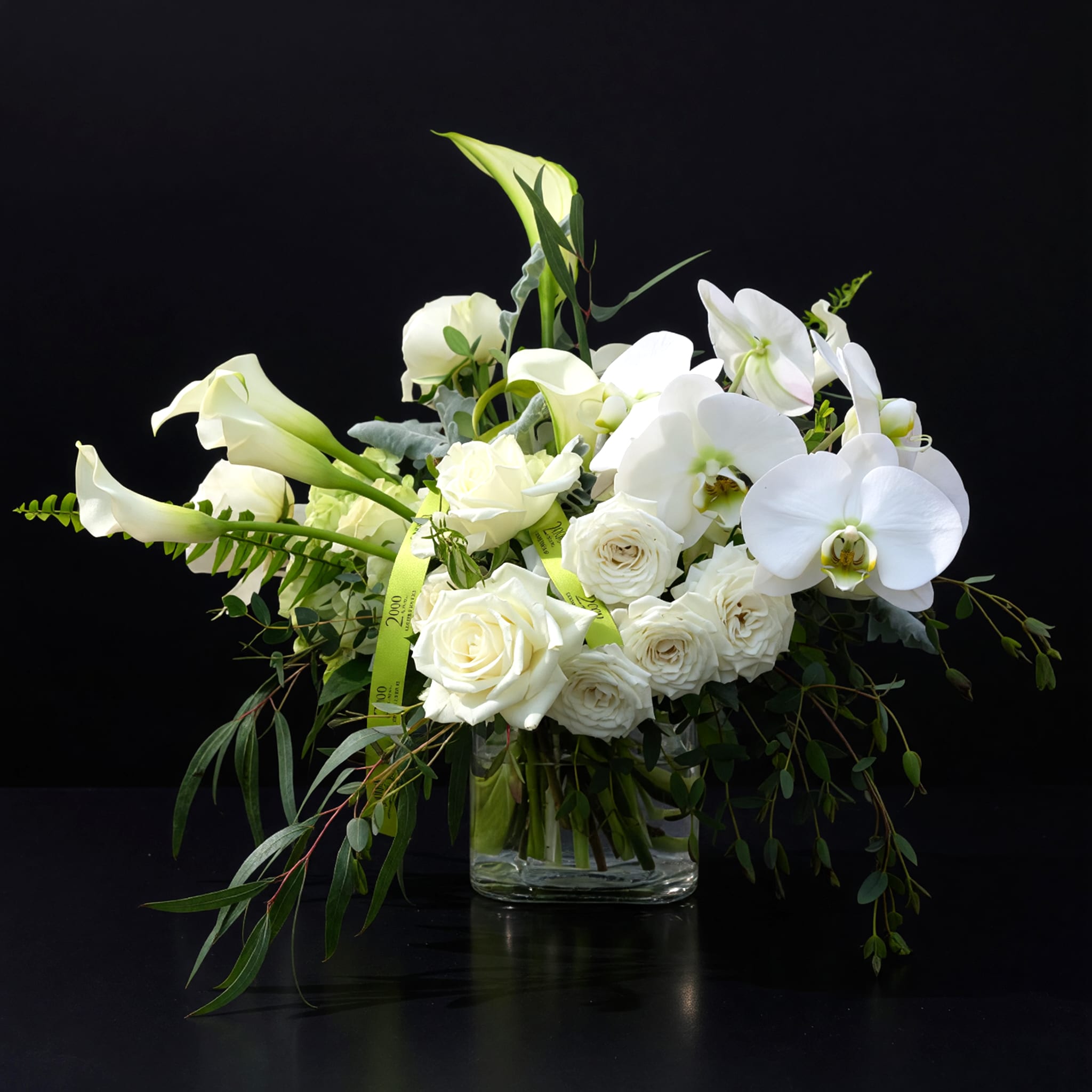 Blanca - Joyful composition of white blooms in a variety of sizes and textures that brings joy and the knowing of a better tomorrow. Accented with various seasonal foliages. Presented in a clear glass container with exposed stems.