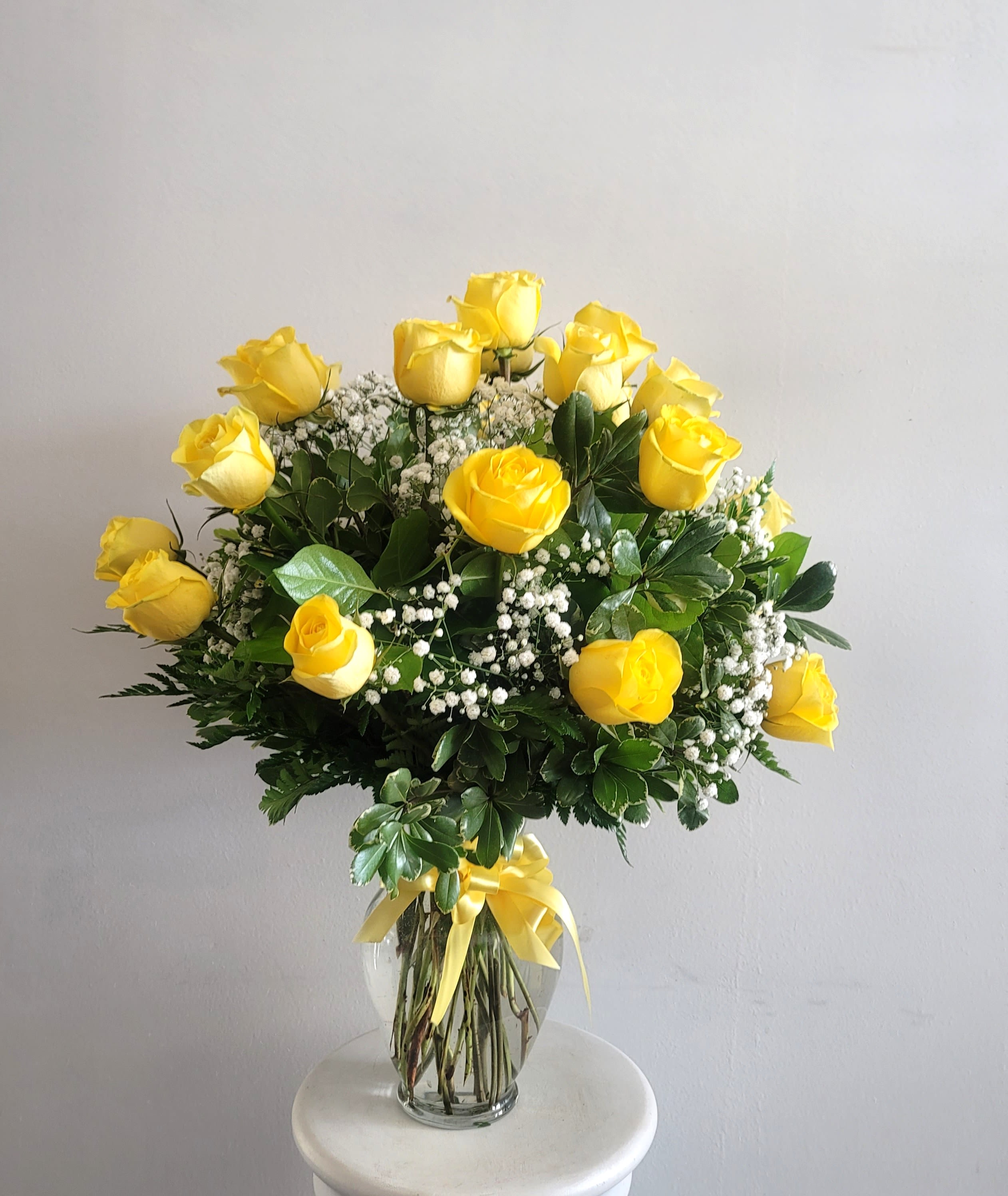 Yellow roses arranged in a clear glass vase with baby's breath
