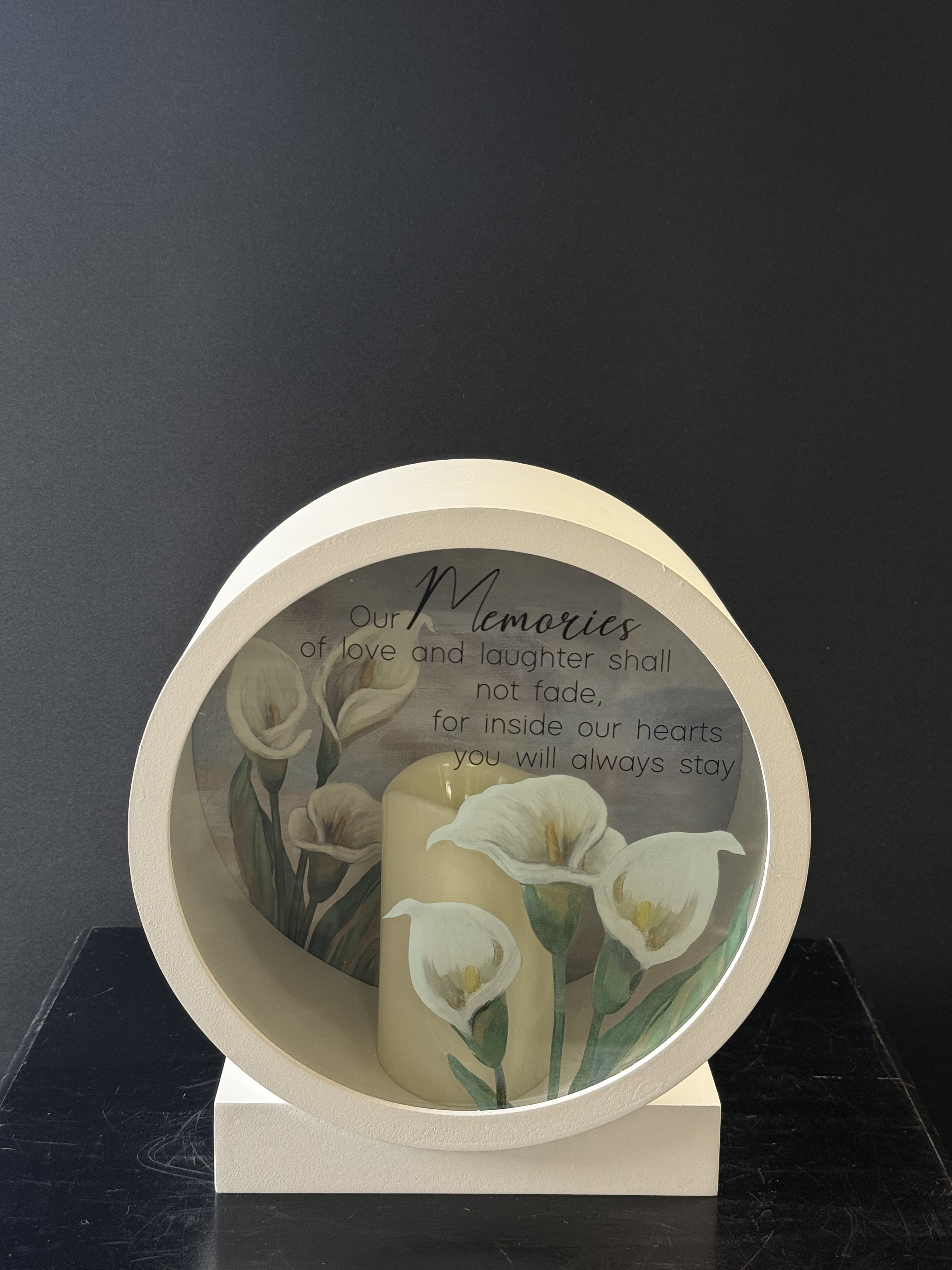 Memorial candle display with white calla lilies and a remembrance message