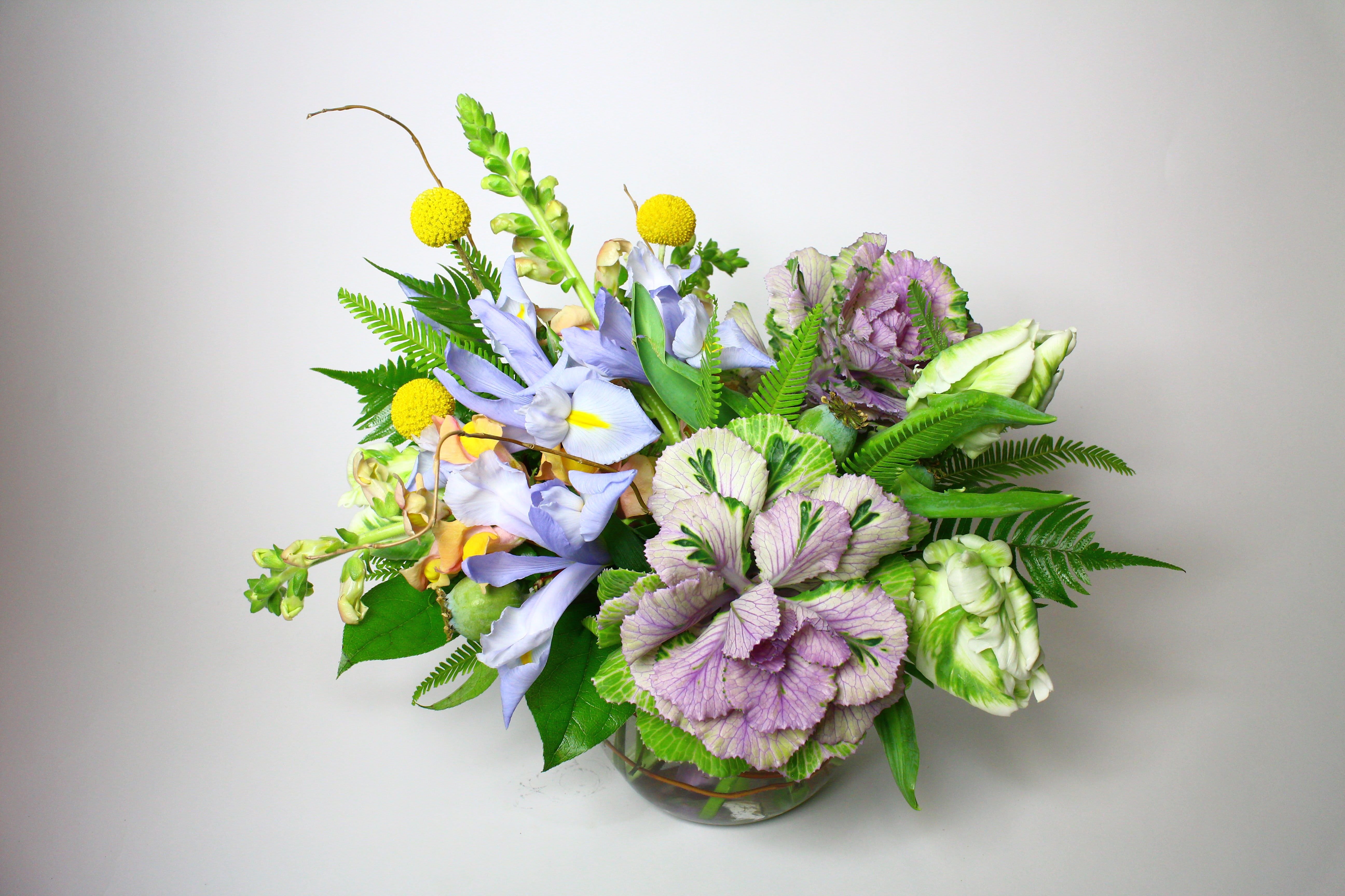 Mixed bouquet of lavender, purple, and yellow flowers in a glass vase