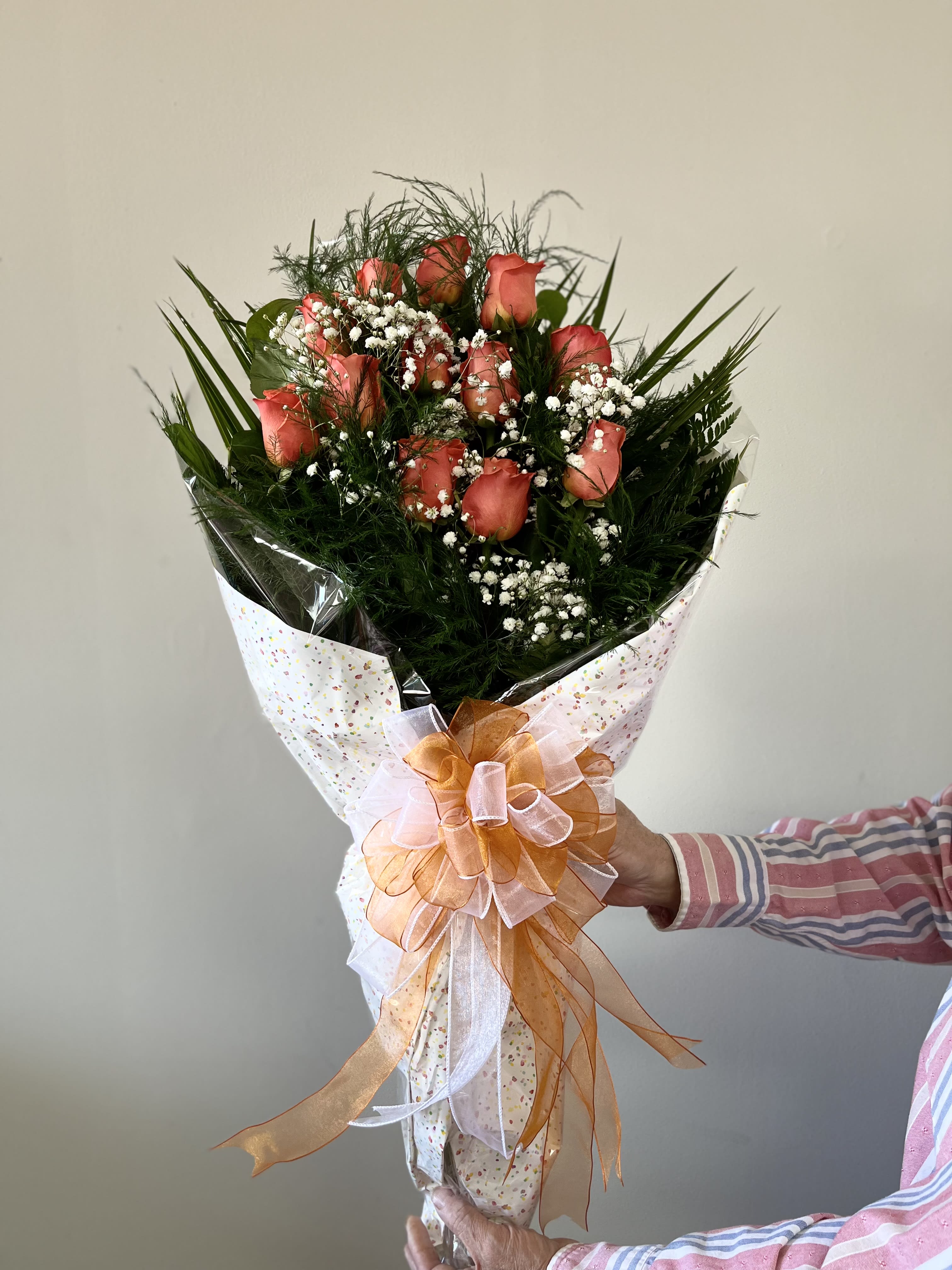 Bouquet of coral roses with baby's breath and a large ribbon