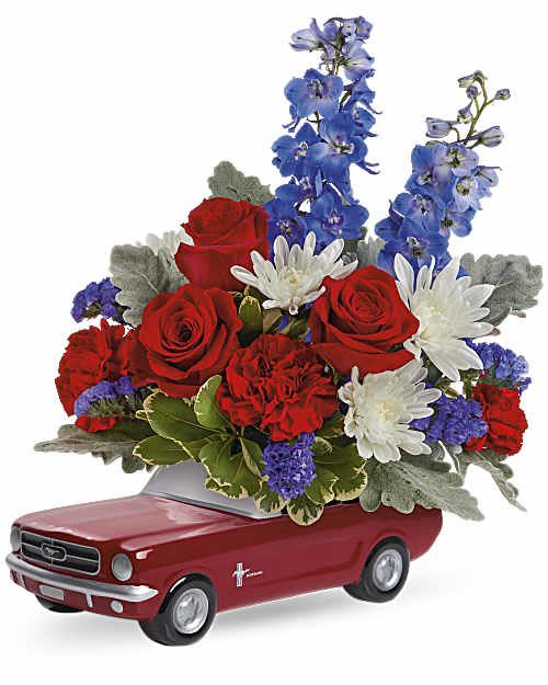 Ford Blossoms Bouquet - The fastest way to their heart is this stylin' ceramic '65 Mustang, brimming with a radiant red, white and blue bouquet. This arrangement includes red carnations, blue delphinium, white cushion spray chrysanthemums, blue sinuata statice, dusty miller and variegated pittosporum. Delivered in Teleflora's '65 Ford Mustang Keepsake. Orientation: All-Around