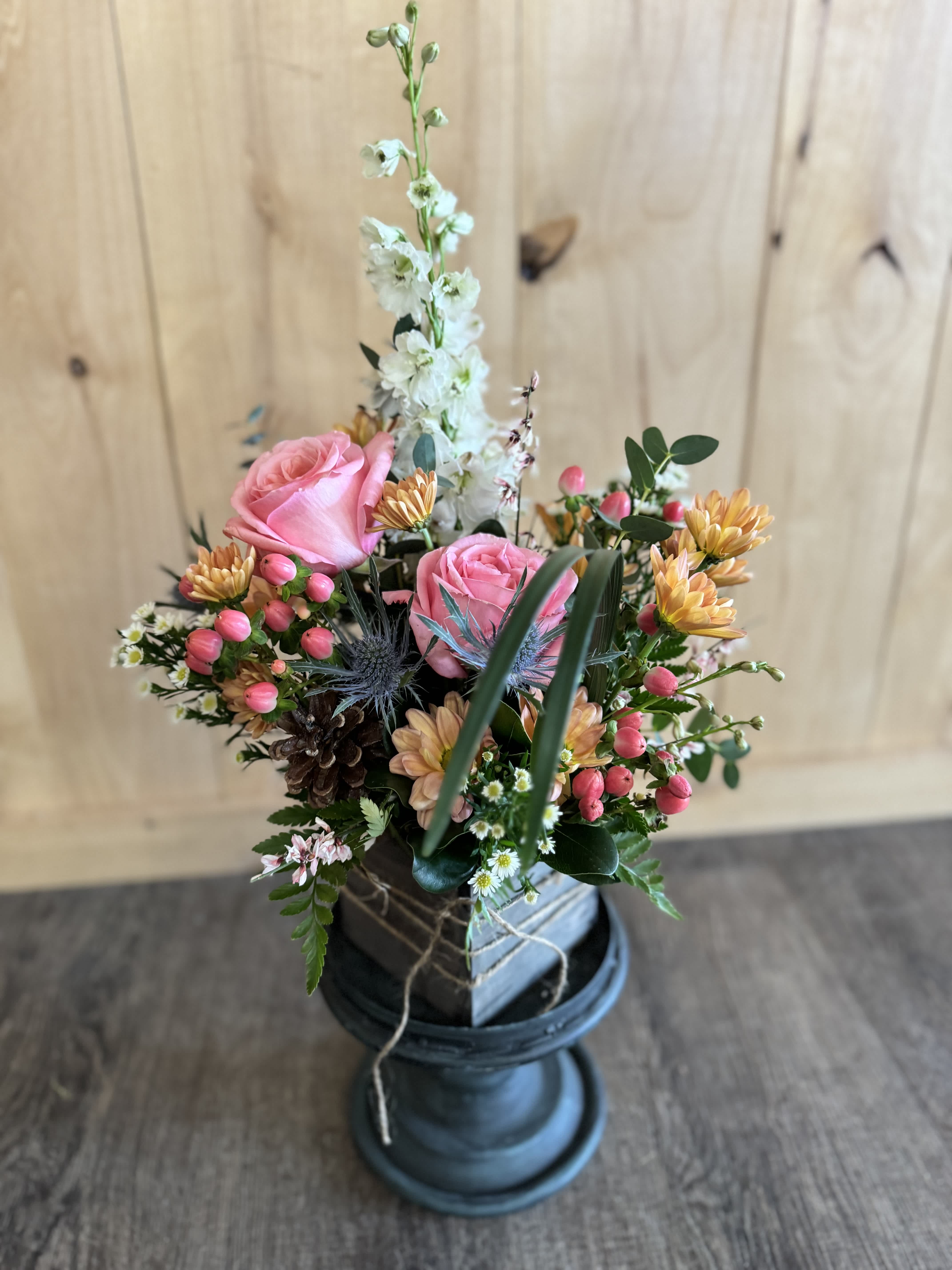 Pink roses and mixed flowers arranged in a dark vase