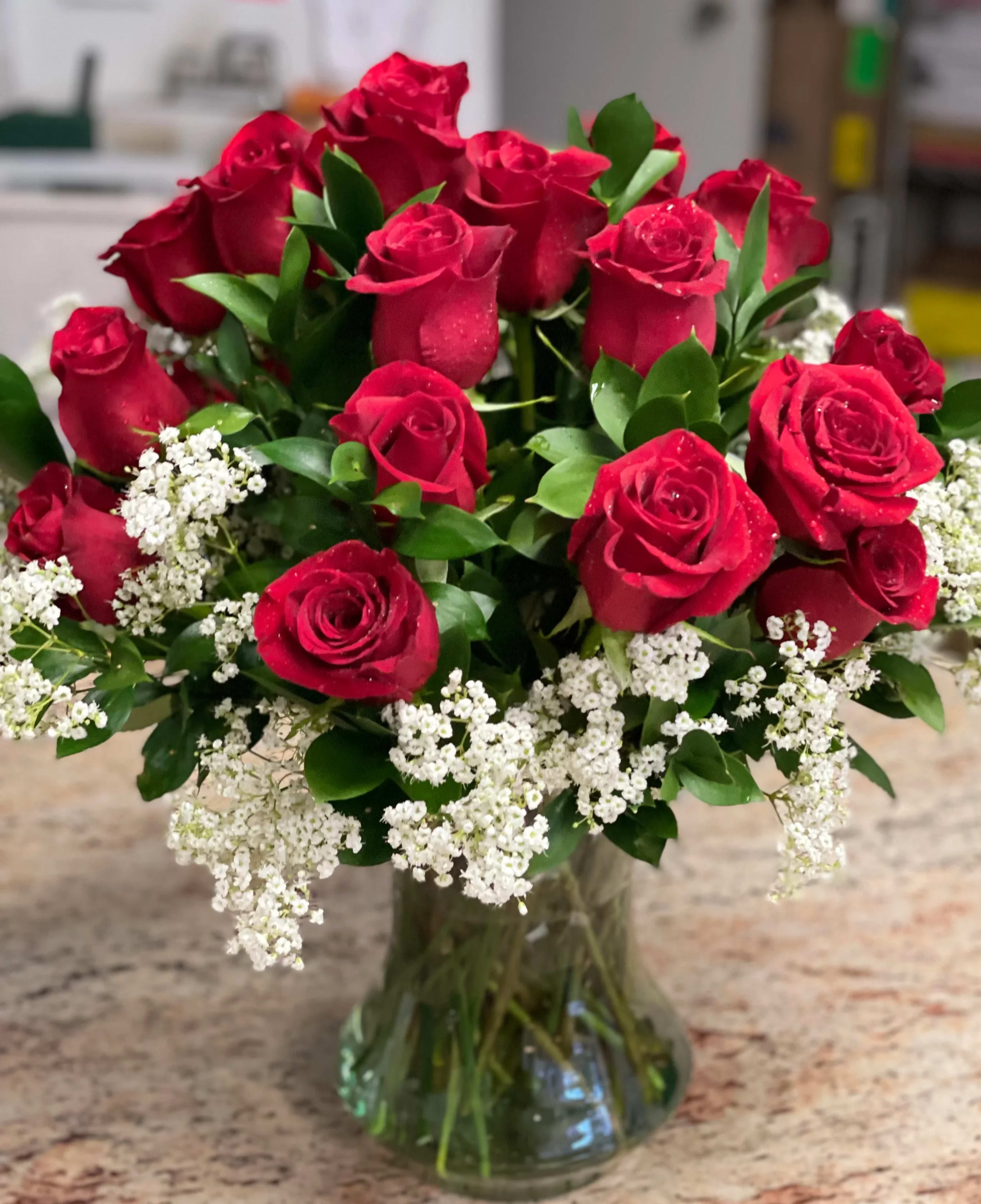 Bouquet of red roses and white baby's breath in a glass vase