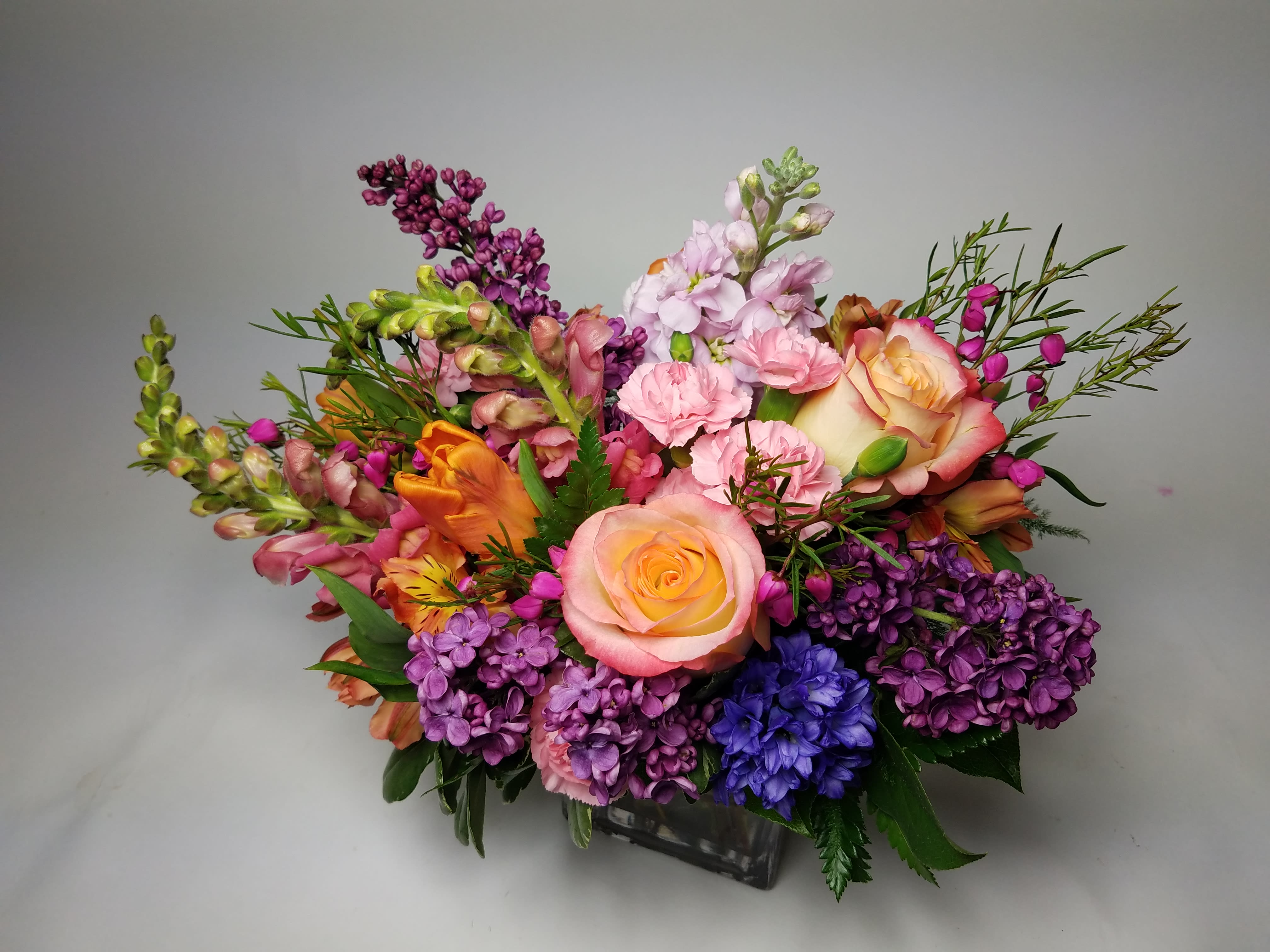 Citrus Seltzer - An elegant and colorful bouquet in a lush style is low and sprawling. Perfect for a pick-me-up or anyone with a love of vibrance!  Seasonal to the spring/early summer months this arrangement will look closest to the photo between March-June