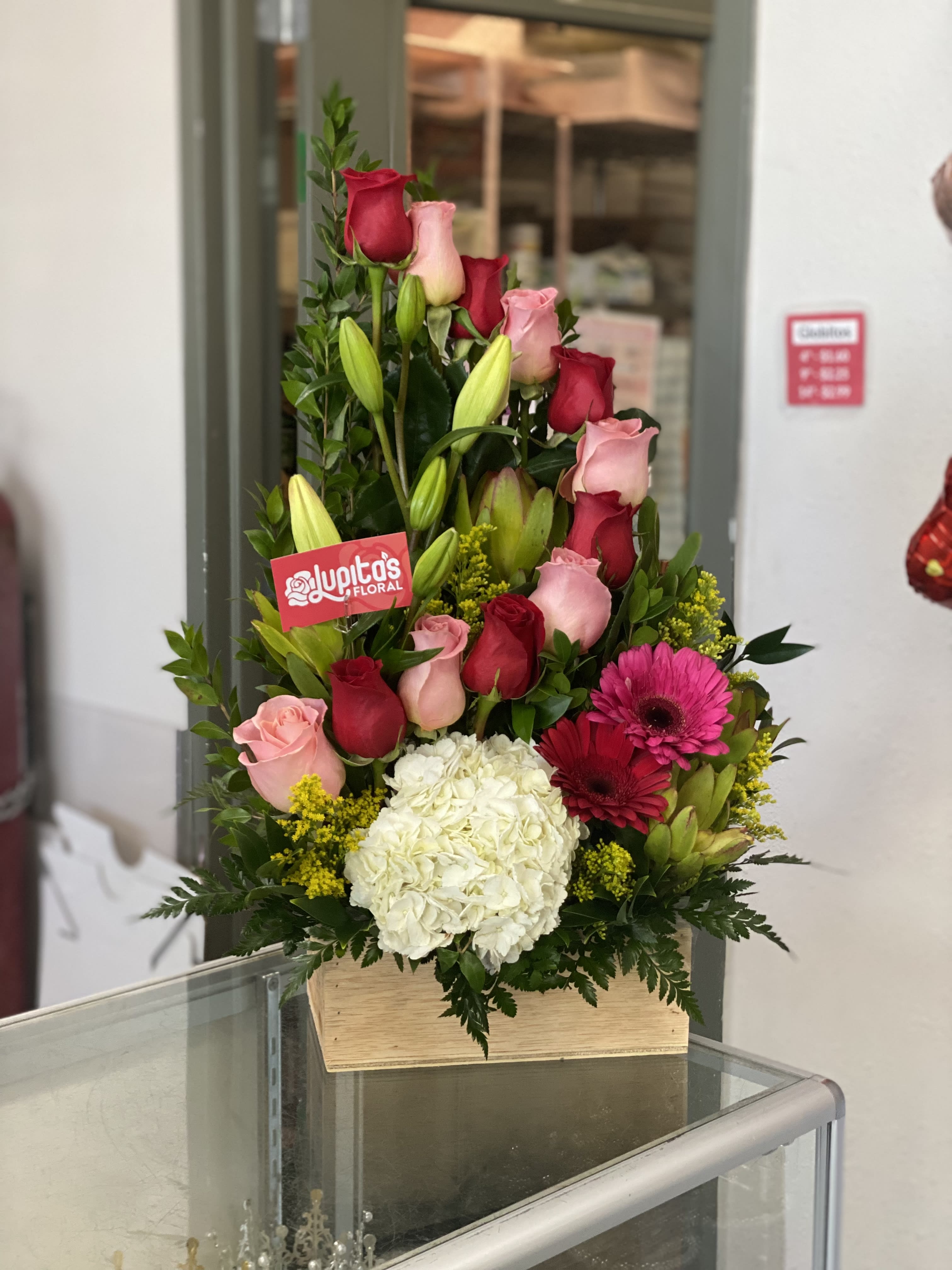 Tall bouquet of pink and red roses with white hydrangea in a wooden box