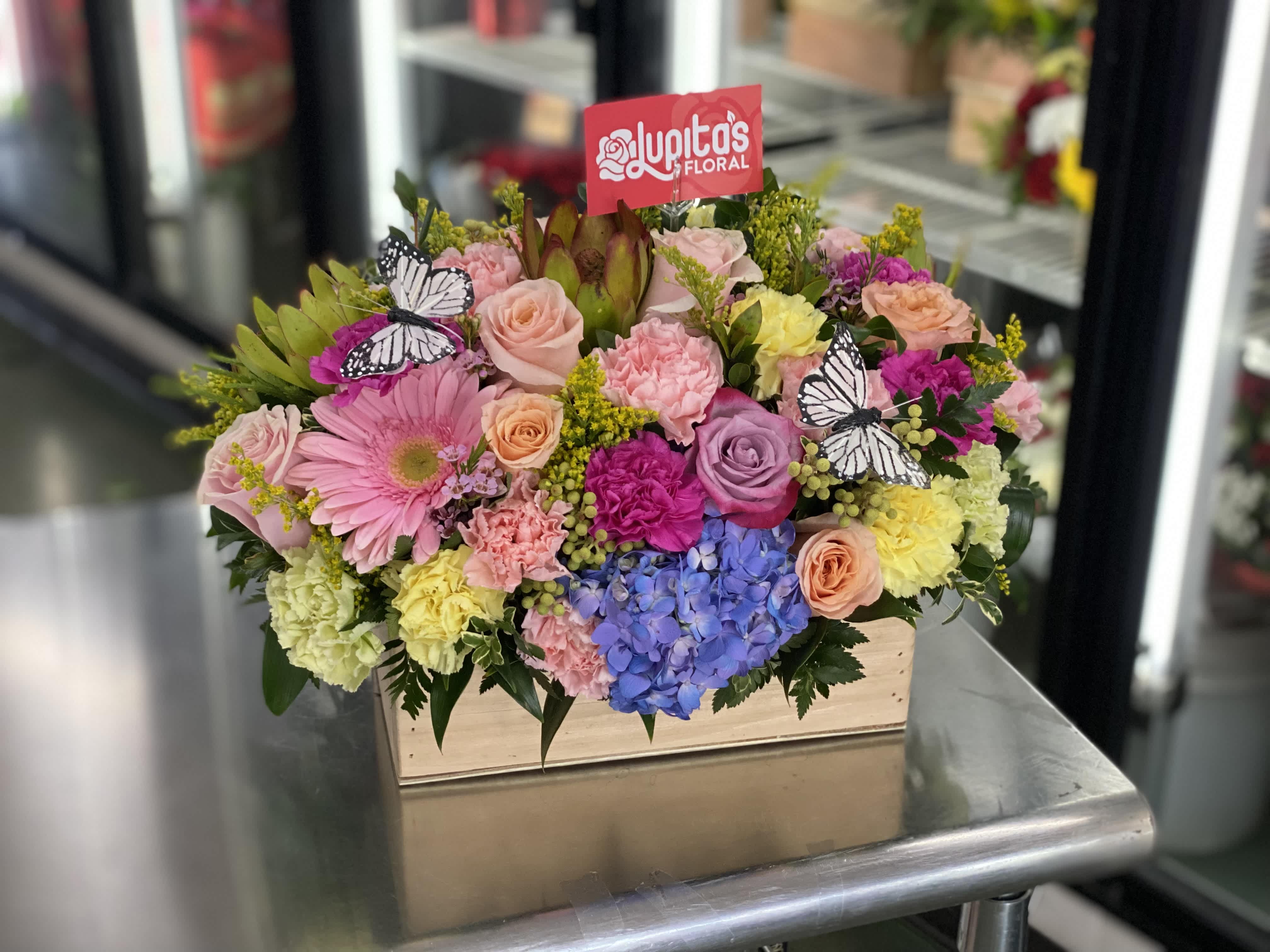 Mixed bouquet in a wooden box with pink, yellow, purple, and blue flowers