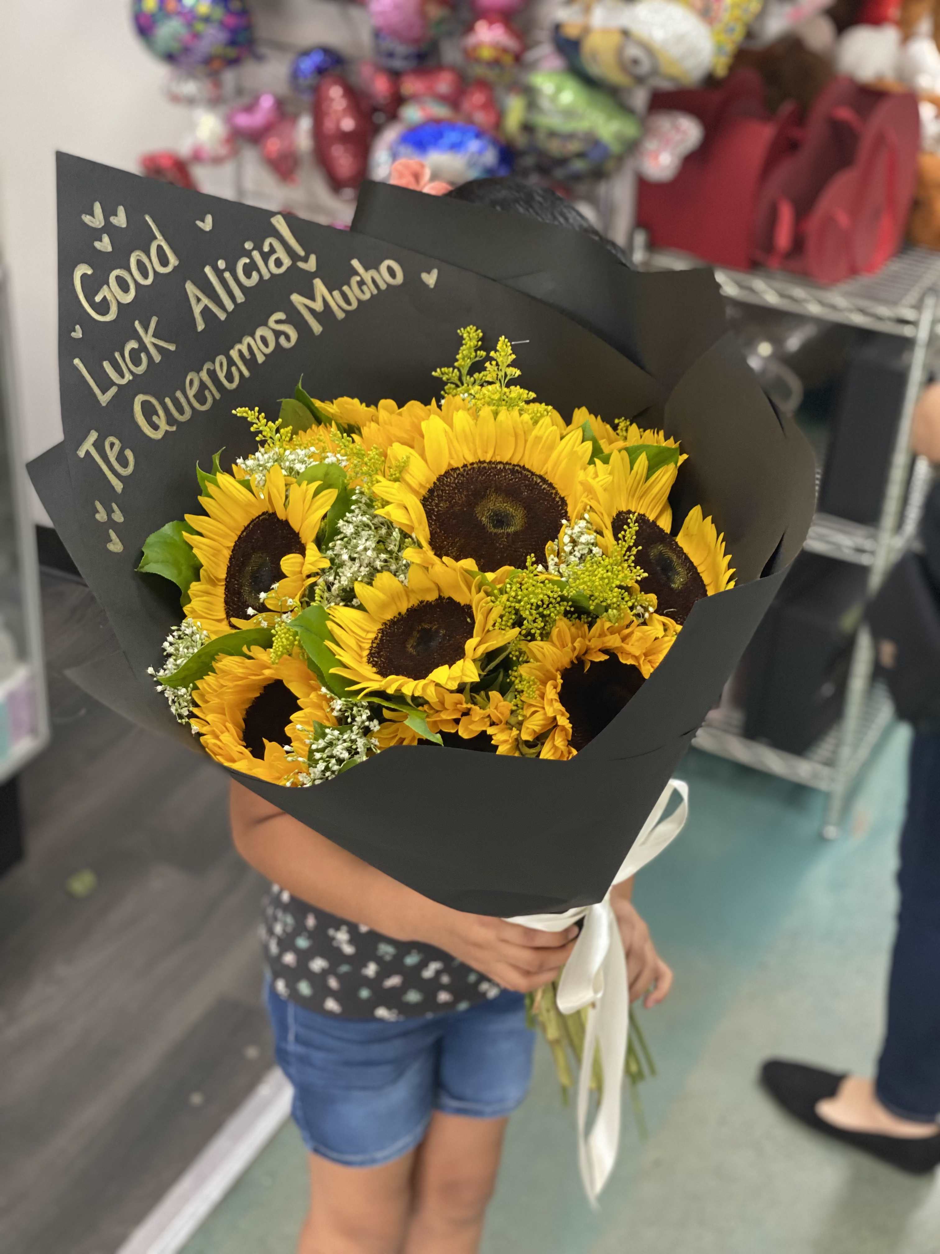 Bouquet of yellow sunflowers wrapped in black paper with a white ribbon