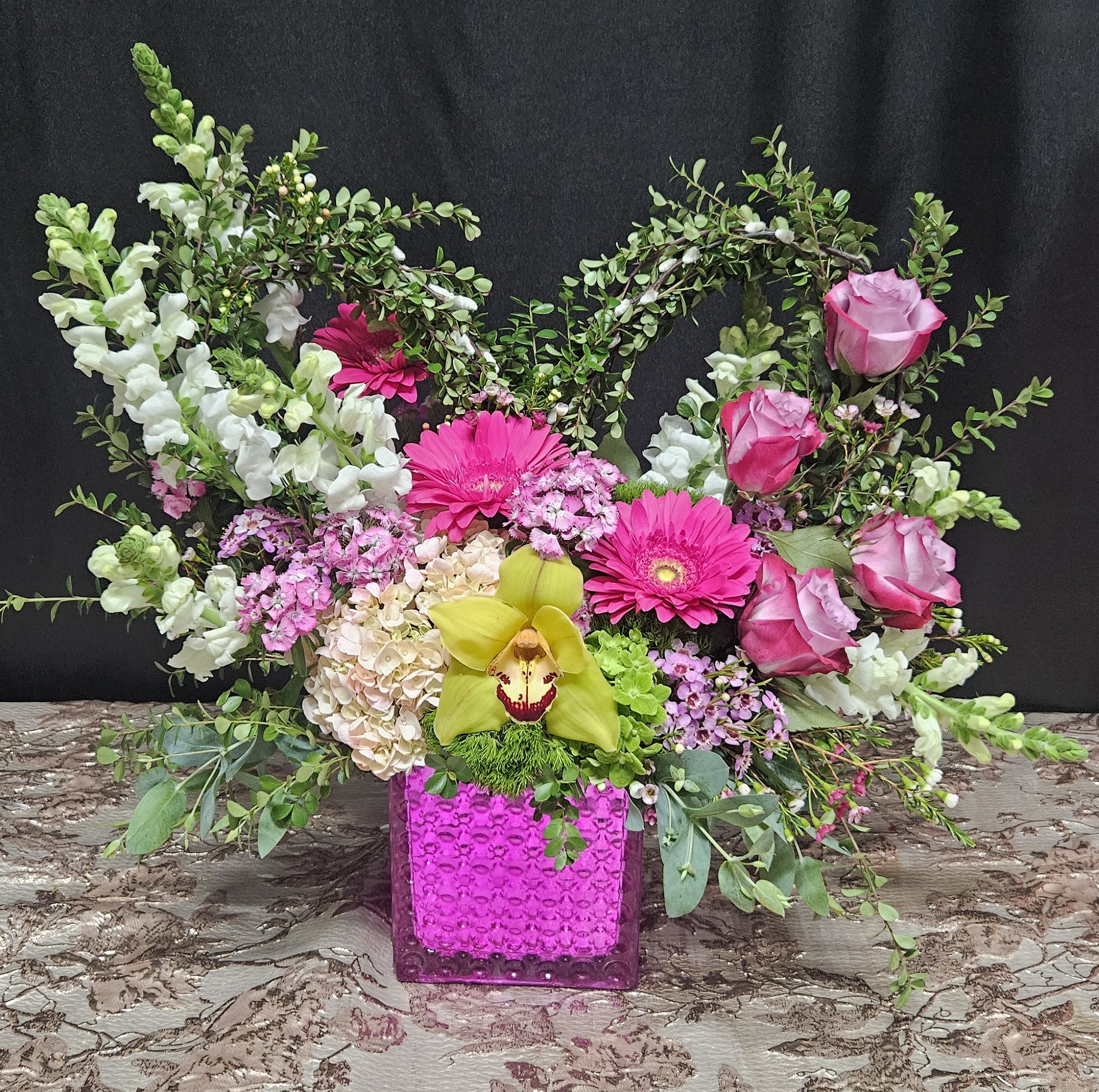 Pink and white floral arrangement in a bright magenta vase