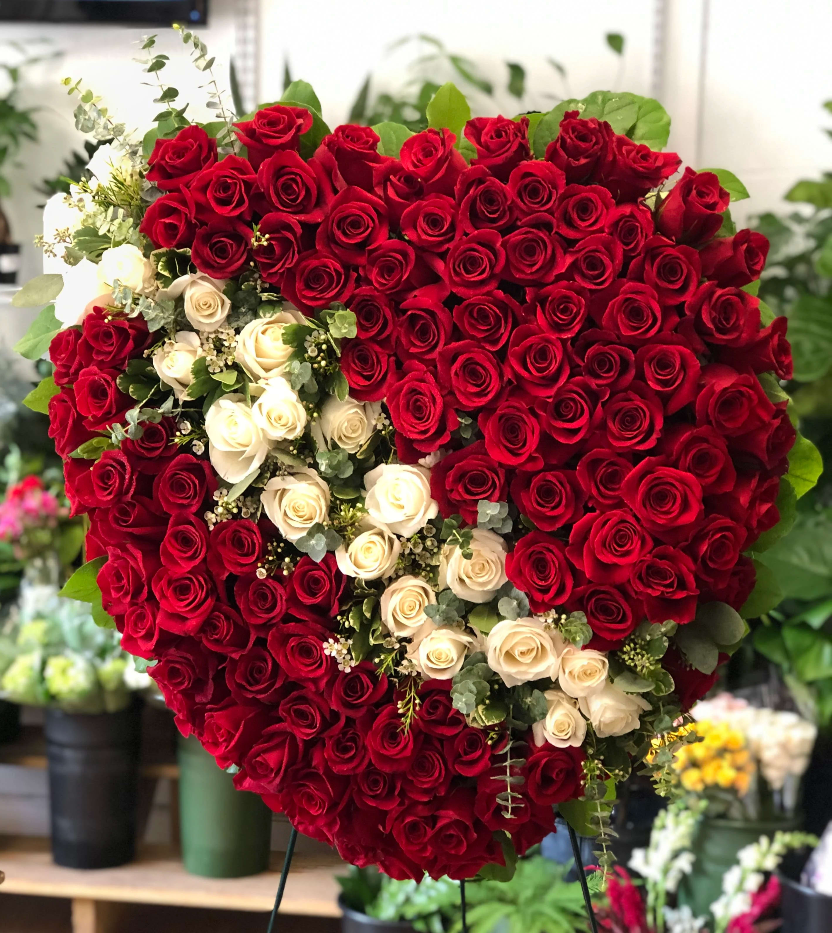 Heart-shaped arrangement of red and white roses on a stand