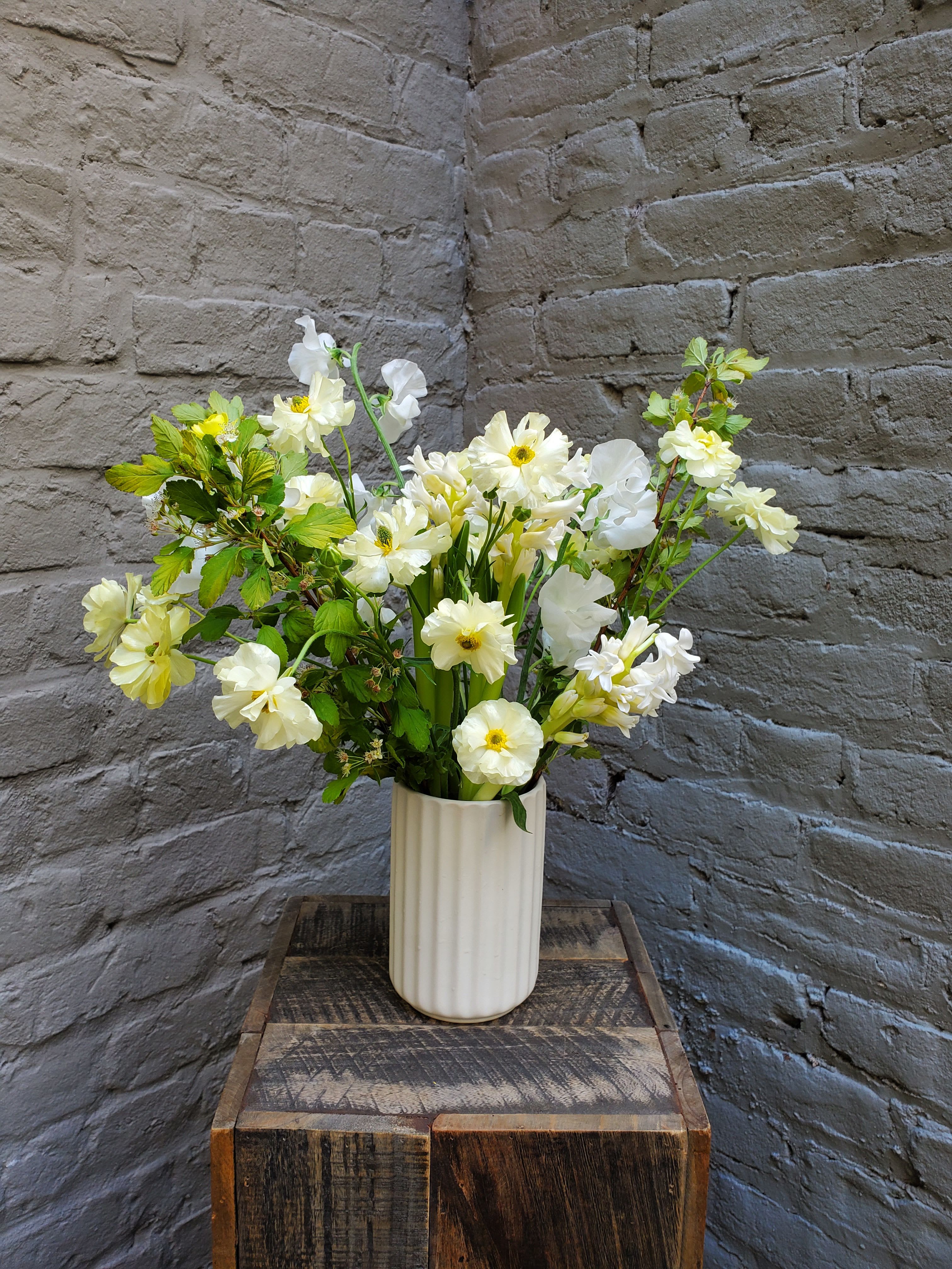 Butterfly Kisses - A gentle spring breeze between dancing petals -- airy white and pale yellow blooms flutter as delicately as a butterfly's wing in this whimsical garden-styled arrangement.  A fluted white ceramic vase displays locally-grown butterfly ranunculus along with fragrant sweet peas and hyacinth, making this a classic and perfectly-composed gesture to the one you love.  Arrangement measures approximately 16x16".