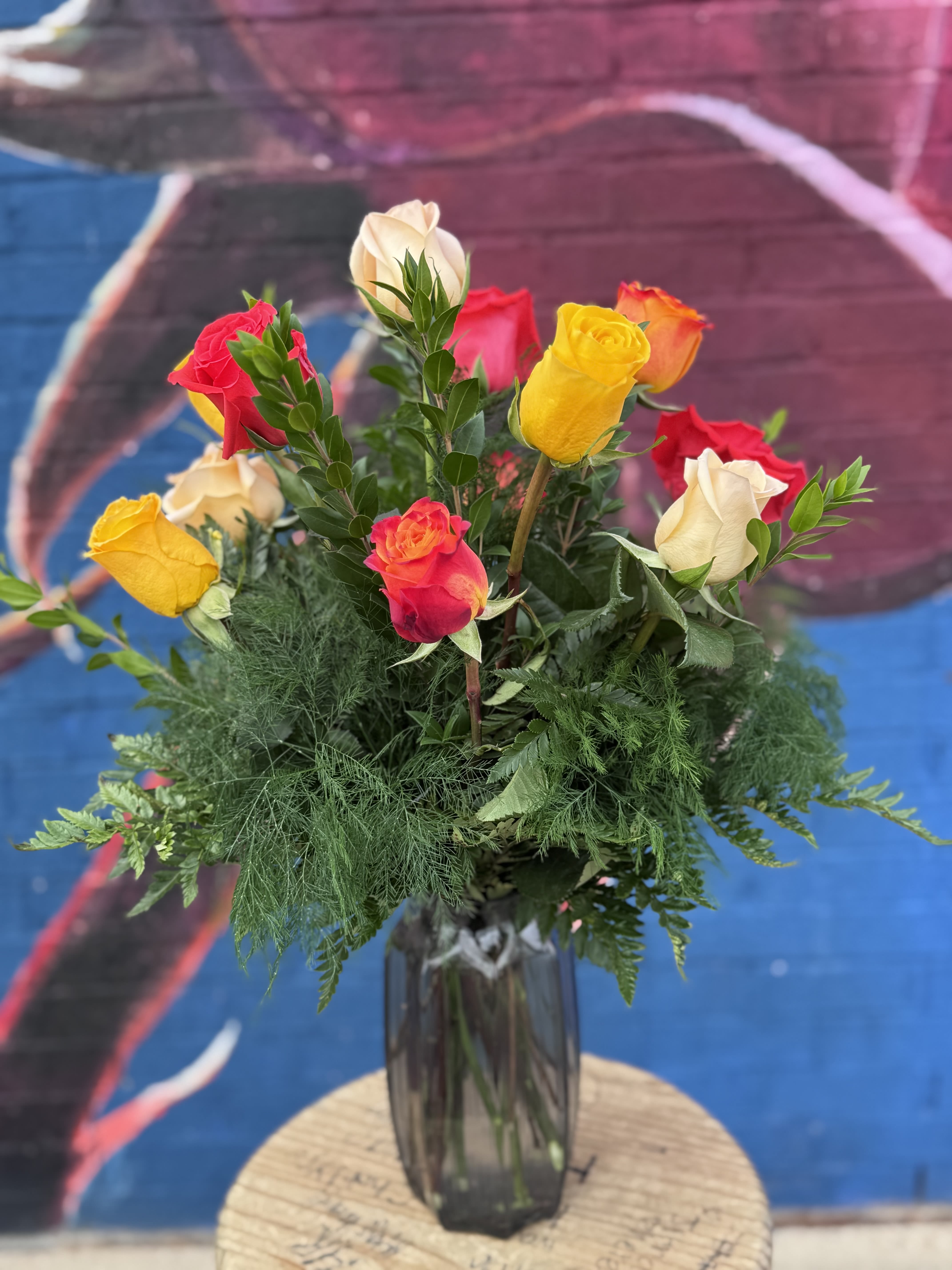 Mixed roses in a tall glass vase with greenery