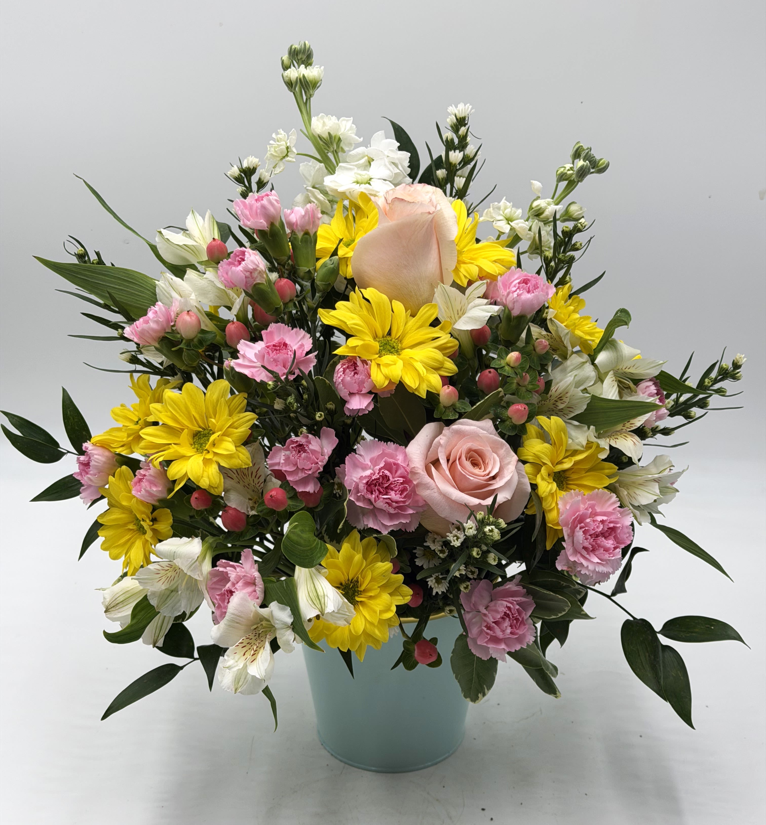 Pink Lemonade - A cheerful blend of yellow daisies, soft peach roses, light pink mini carnations &amp; more designed in a pastel colored ( Color will vary! ) container with gold rimmed edge. Pink Lemonade brings warmth, happiness and a touch of sweetness to any celebration!