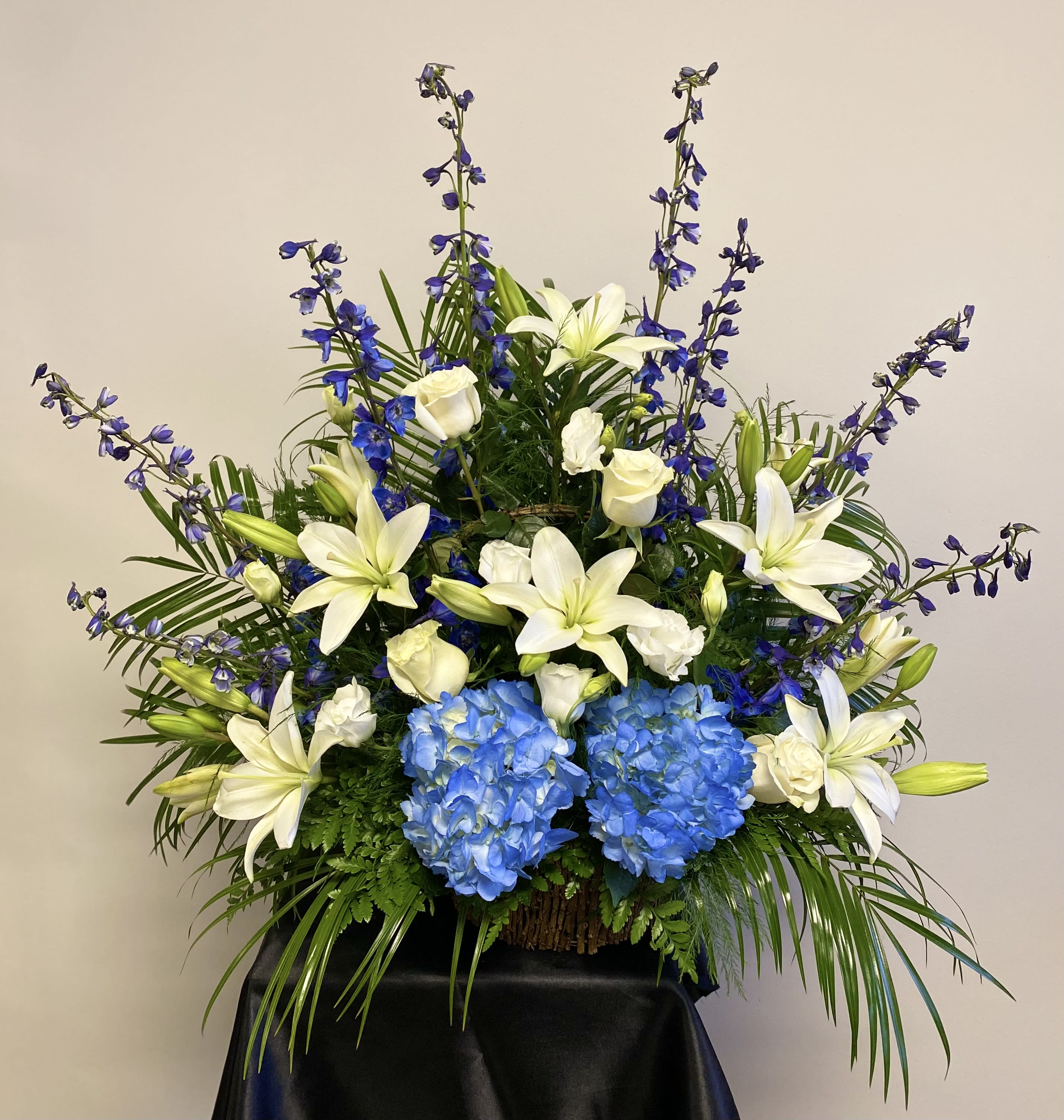 Large floral arrangement with white lilies, blue hydrangeas, and purple flowers