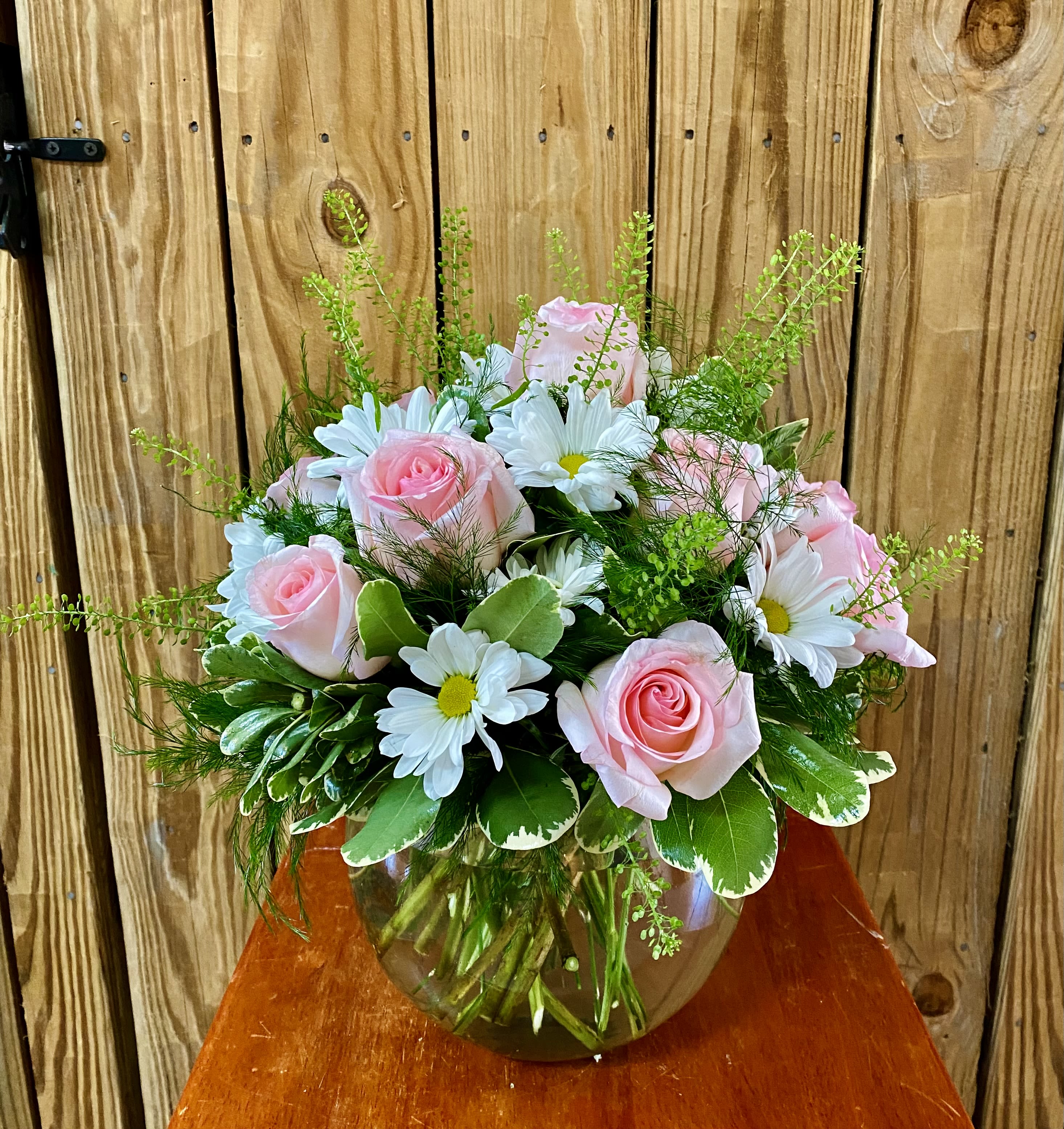 Pink roses and white daisies arranged in a glass vase