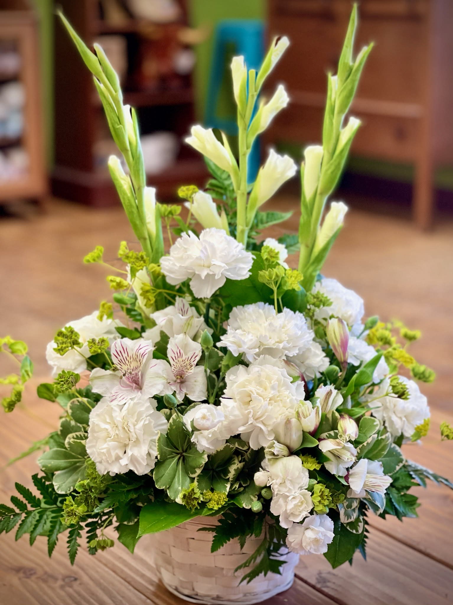 Eternal Love Basket - The crisp white Eternal Love basket is the perfect way to send your heartfelt sympathies. Stately white gladiolus, softly curled carnations and delicate Peruvian lilies come together in a white bamboo basket, perfect for a home or for a service.  
