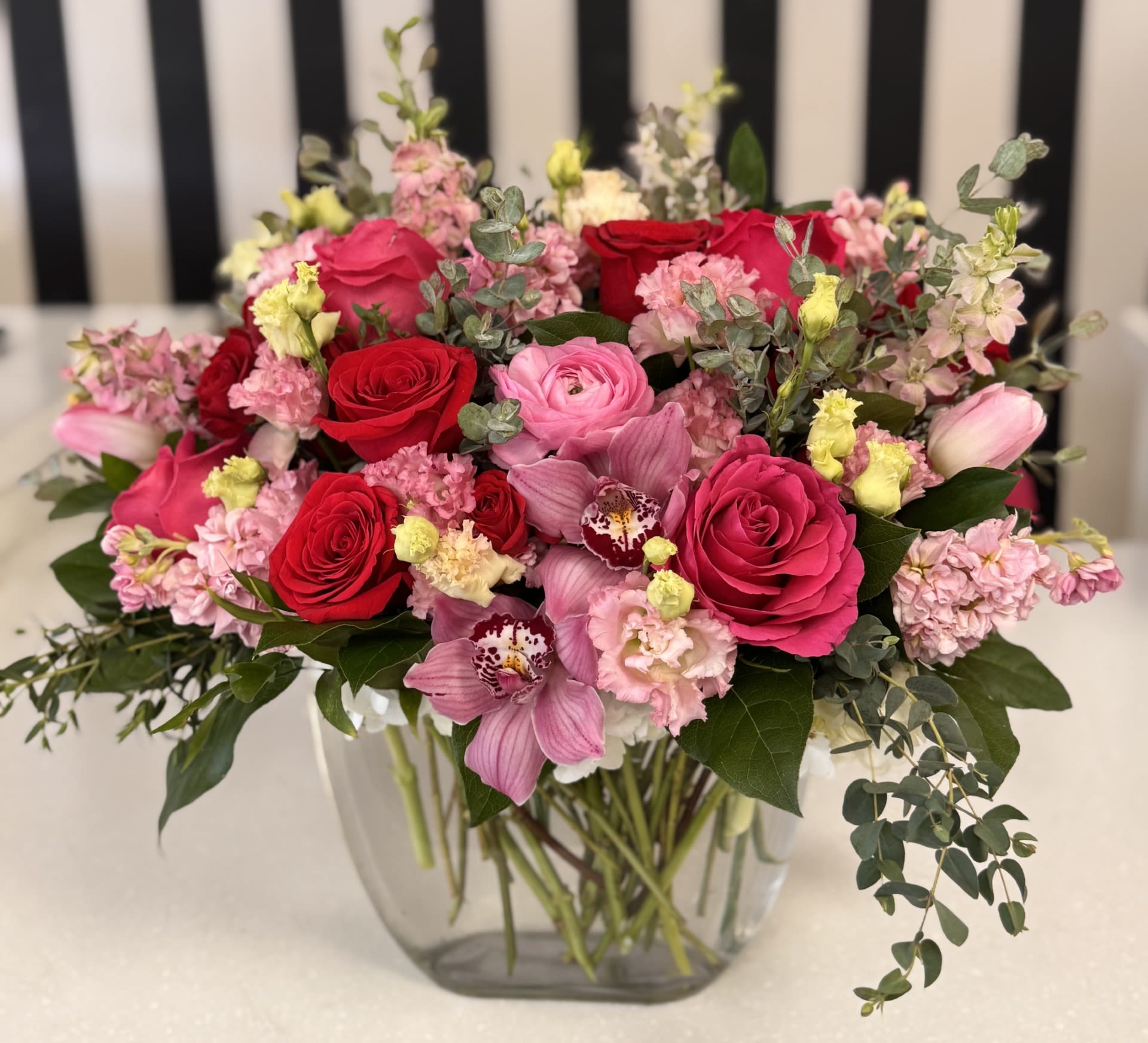 Mixed pink and red flower bouquet in a clear glass vase