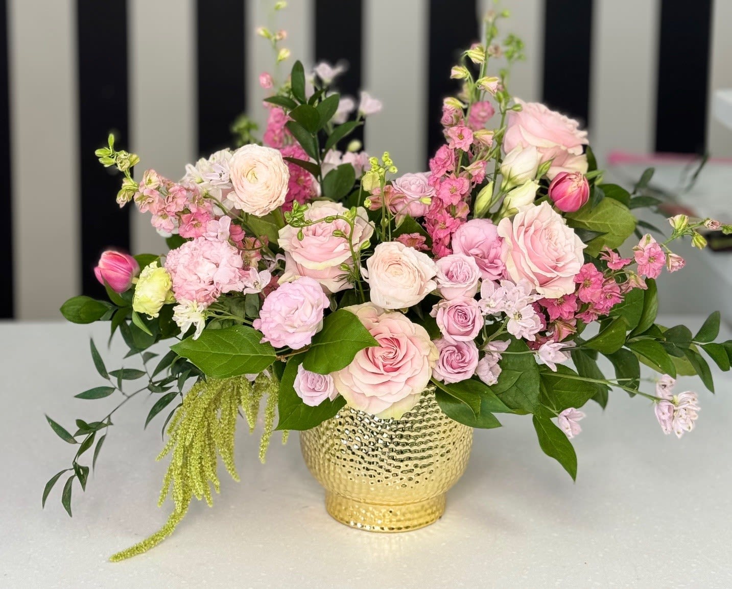 Pink and white floral arrangement in a gold vase