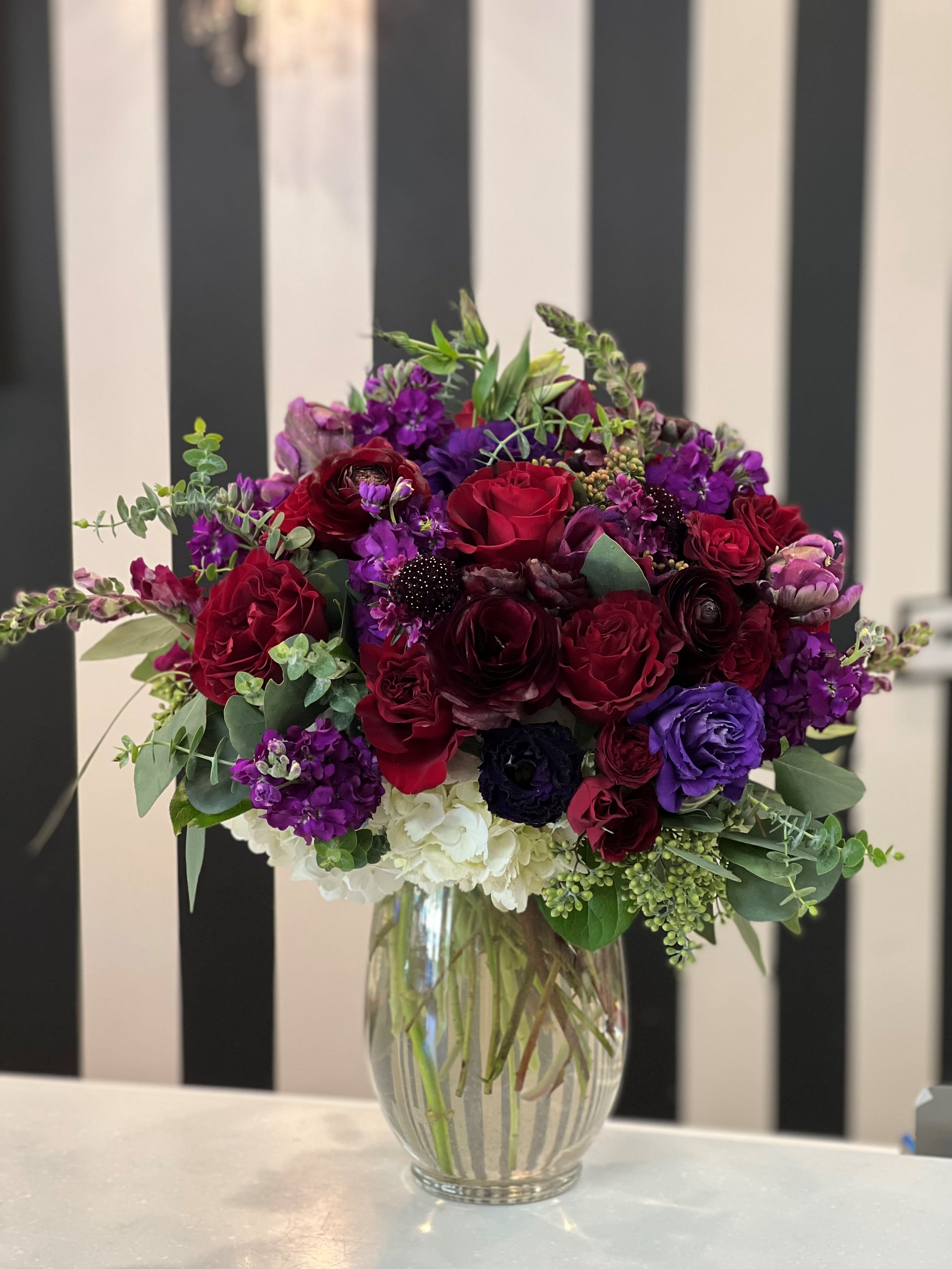 Bouquet of red, purple, and white flowers in a clear glass vase
