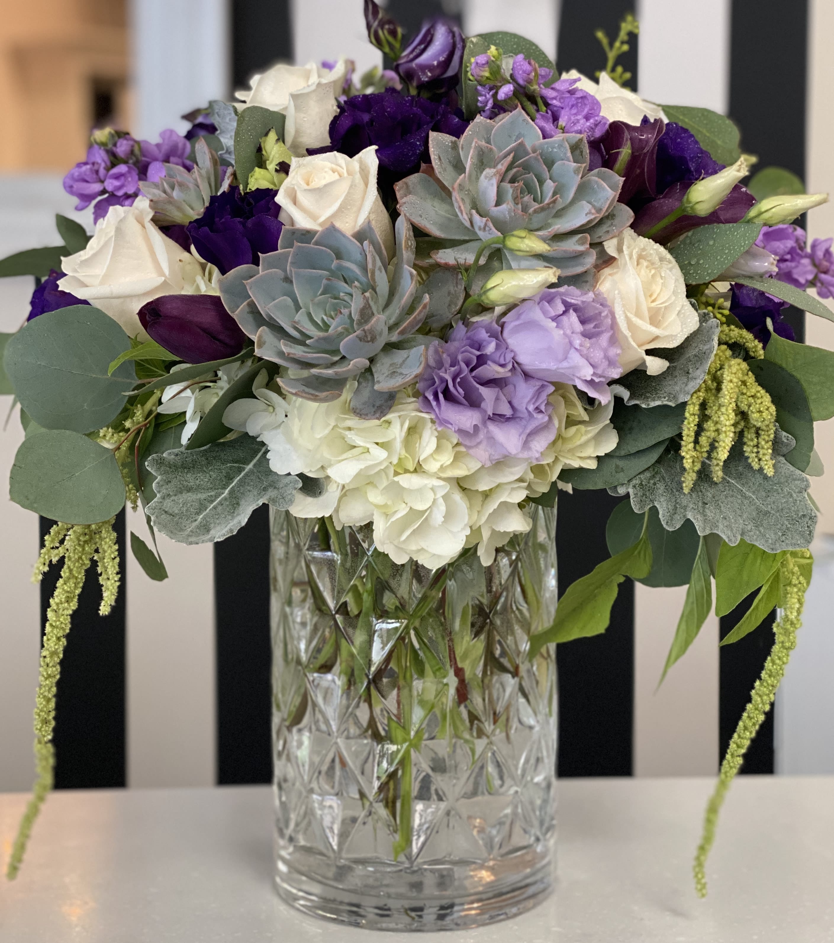 Purple and white floral arrangement in a clear glass vase