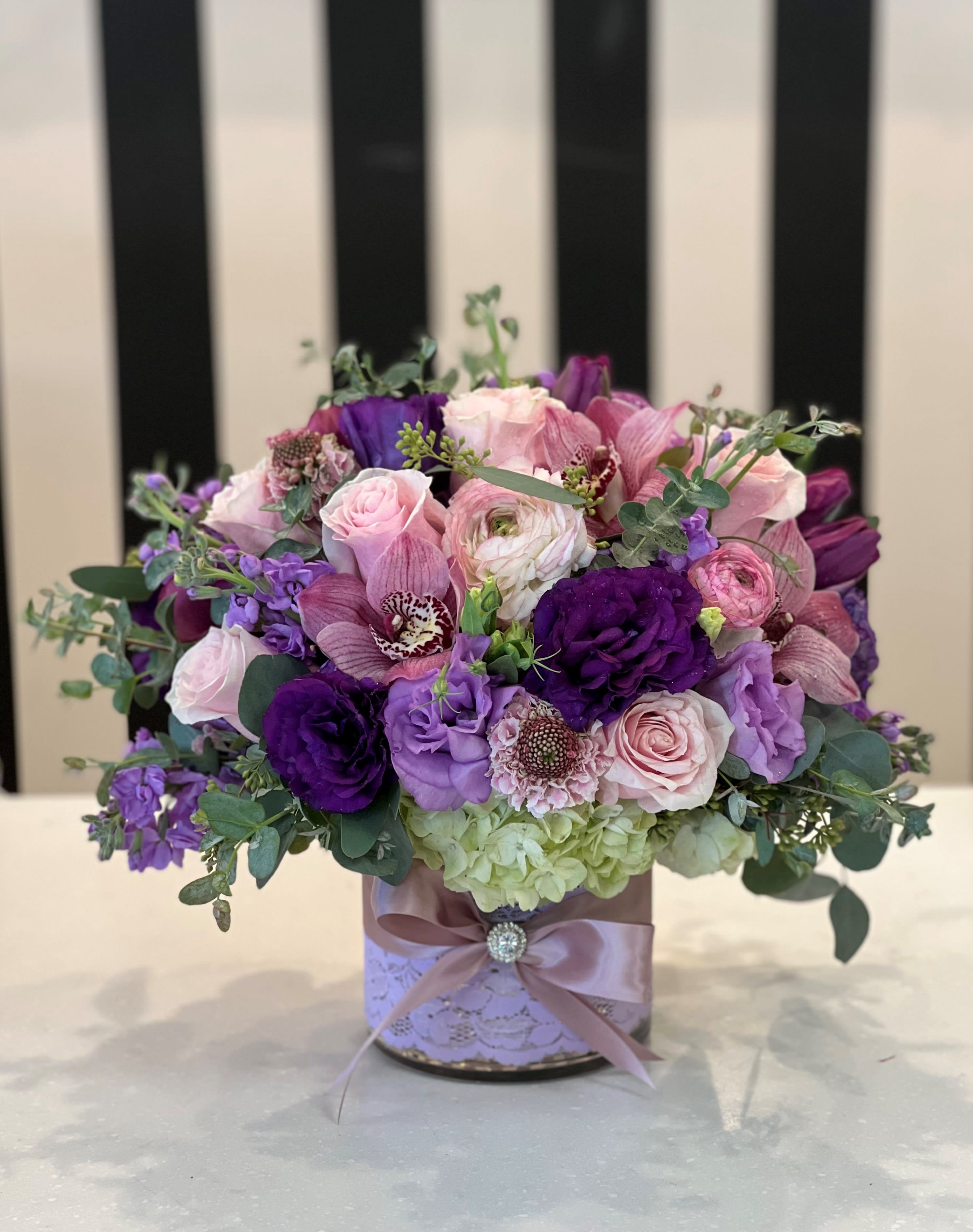 Pink and purple bouquet in a decorated round box