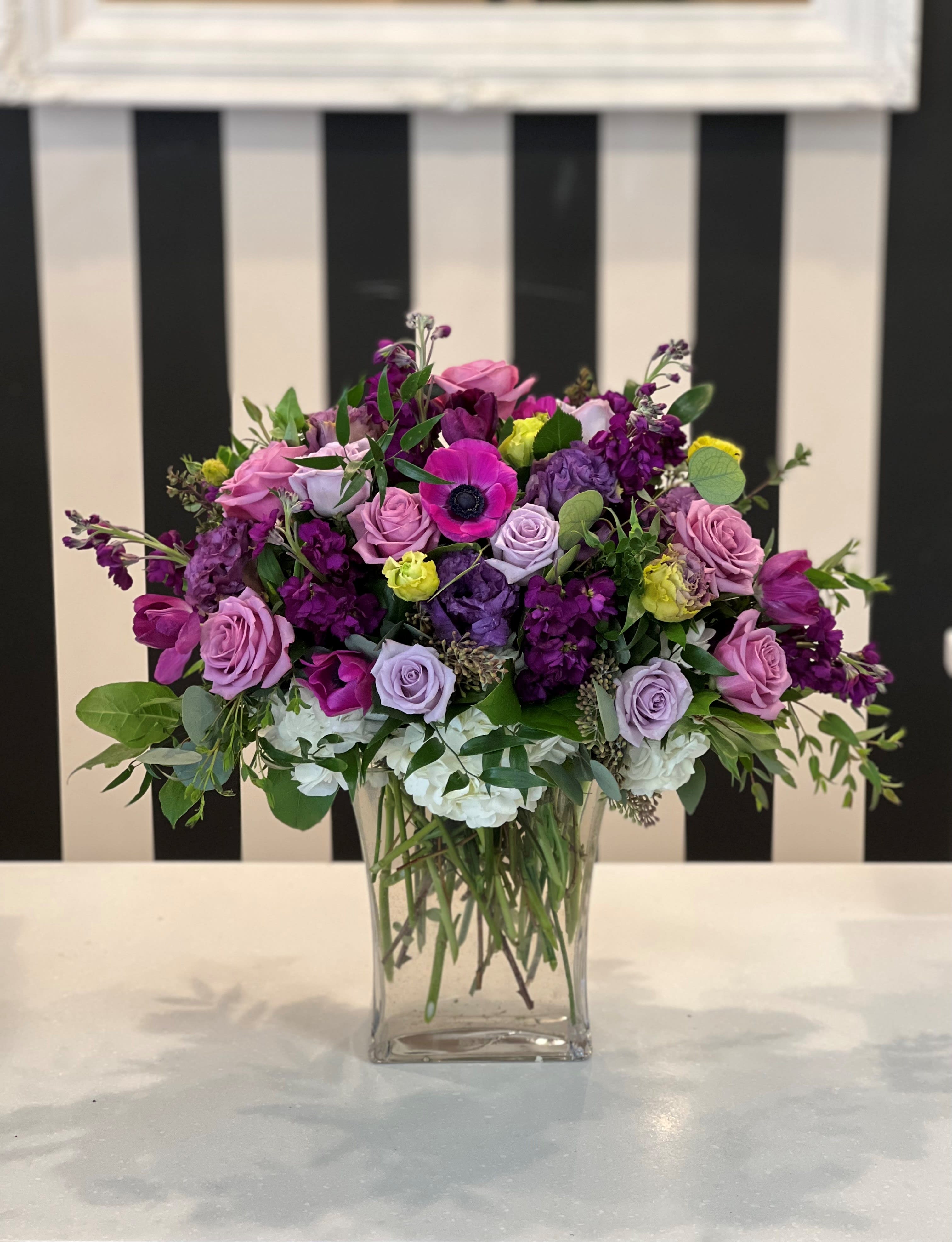 Mixed purple and pink flower arrangement in a clear glass vase