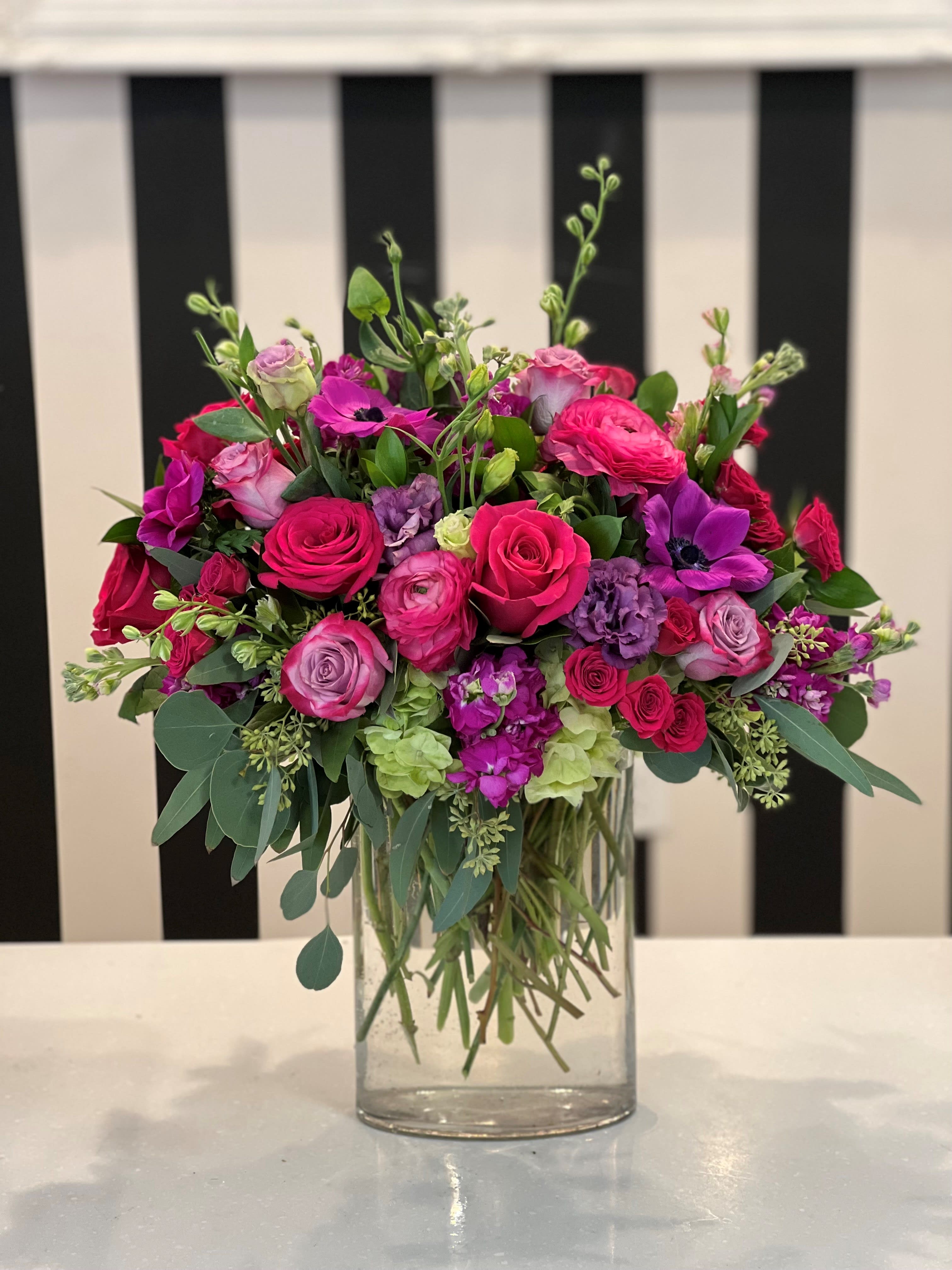 Pink and purple mixed flower arrangement in a clear glass vase