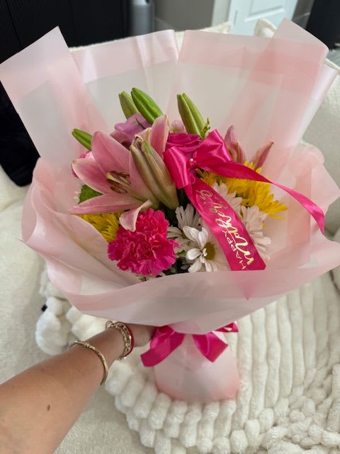 Pink lily bouquet wrapped in pale pink paper with a bright ribbon