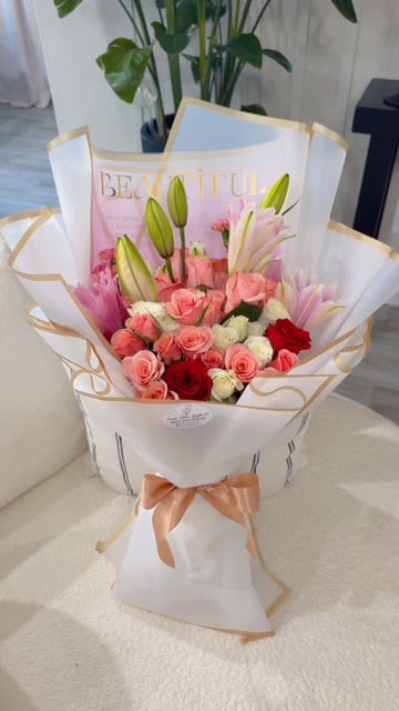 Pink and red rose bouquet with lily buds in white wrap