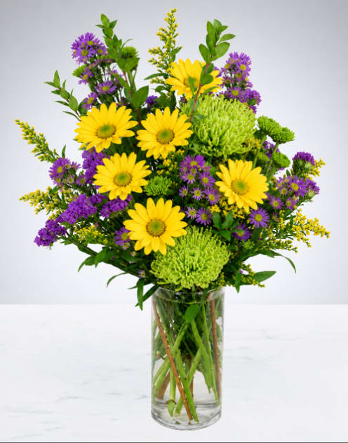 Sunshine &amp; Lavender Garden Bouquet - Bring warmth and happiness to any space with this bright and cheerful arrangement. Designed with a fresh garden-inspired style, this bouquet is full of vibrant color, soft texture, and natural beauty. Arranged in a clear glass vase, it’s the perfect gift for birthdays, celebrations, get well wishes, or simply to brighten someone’s day. A beautiful design that adds a touch of sunshine wherever it’s placed.