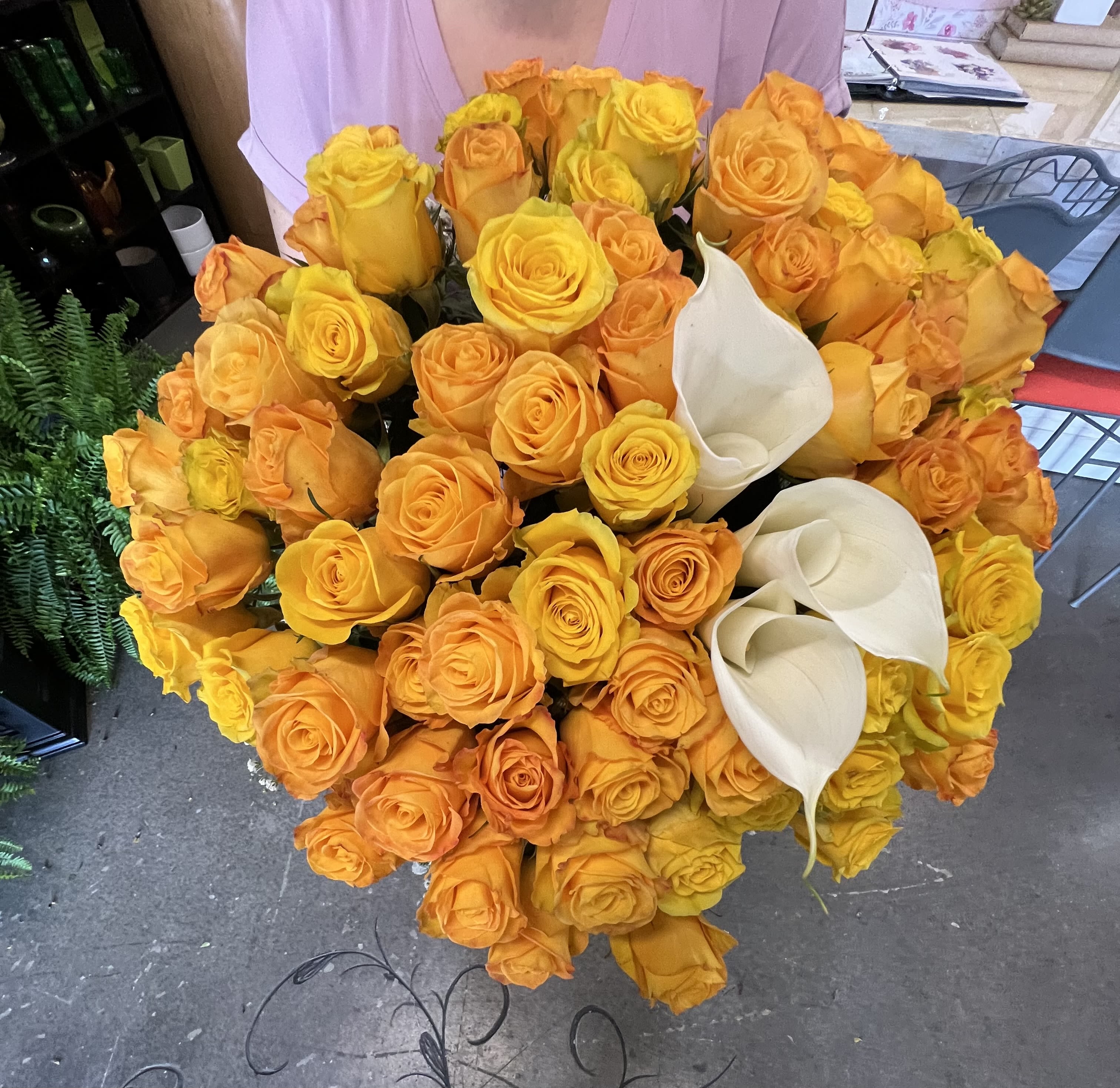 Golden Roses  - A lush, rounded bouquet of golden roses and white calla lilies-perfect as a birthday bouquet or a cheerful anniversary roses gift that feels both warm and refined. The bright orange and yellow roses create an immediate sunlit impression, while the smooth white calla lilies add a striking focal contrast near the center-right, making the recipient feel genuinely celebrated and noticed.  Tightly packed for a full, abundant texture, the arrangement pairs saturated rose petals with the sleek curves of calla lilies for a balance of exuberance and elegance. Colors: orange, yellow, and white; flowers: roses and calla lilies. Sized as a dense, everyday floral arrangement, it's ideal for congratulating someone, saying thank you, or sending affectionate, feel-good wishes-order with standard delivery and simple care: keep water fresh, trim stems every few days, and display away from direct heat for longest enjoyment.