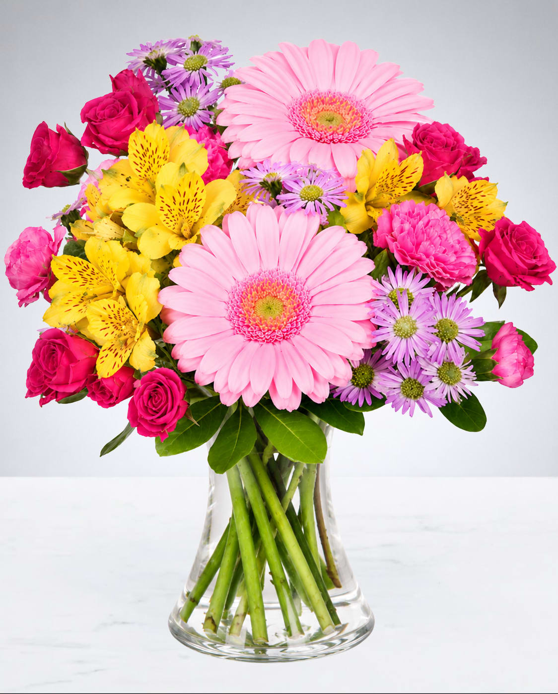 Bright Blooms Delight - Bright, cheerful, and full of charm, this eye-catching arrangement is designed to make any occasion feel extra special. Featuring a beautiful mix of soft pastel tones and vibrant pops of color, this fresh bouquet brings warmth, happiness, and elegance to any room. Styled in a clear bell-shaped vase, it’s the perfect gift for birthdays, celebrations, thank yous, or simply to brighten someone’s day with a little beauty and joy.