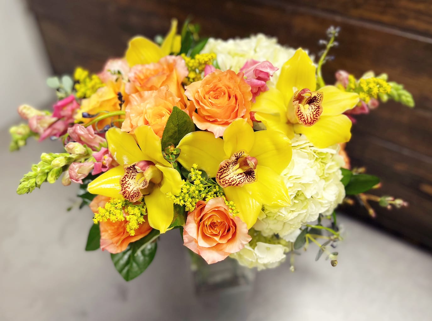 Bouquet of yellow orchids, peach roses, and white hydrangeas
